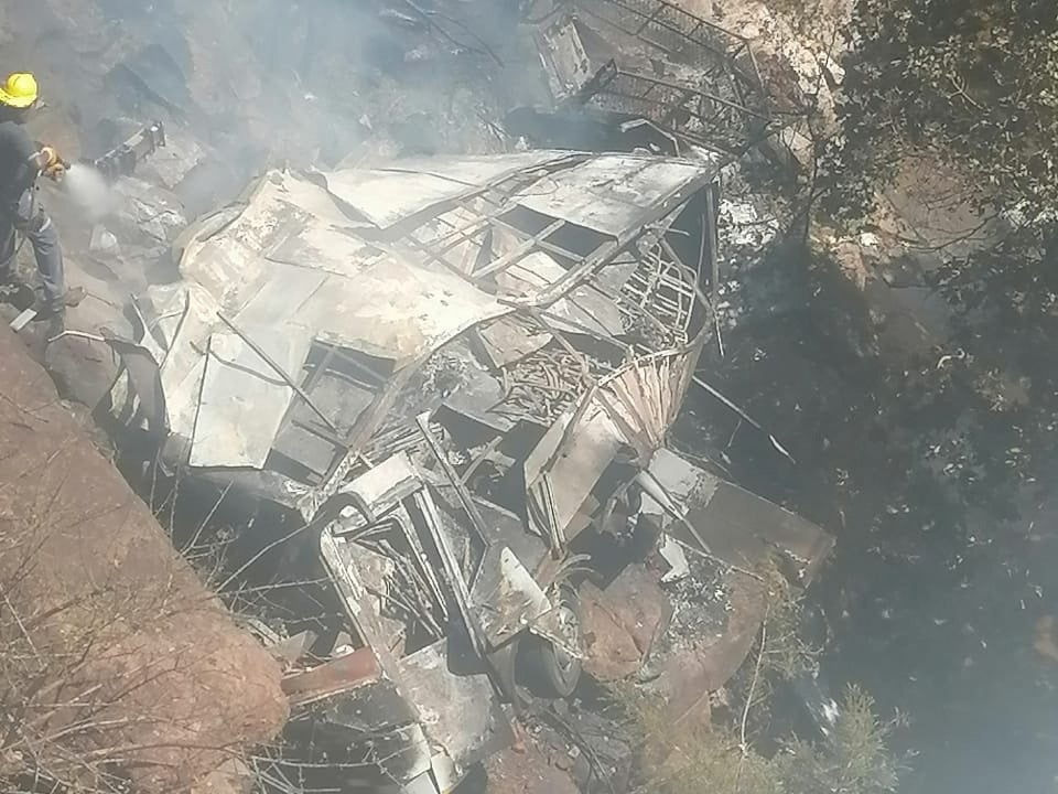 Firefighters hose down a bus after it crashed off the R518, killing a few dozen, in Waterberg District, Limpopo Province, South Africa