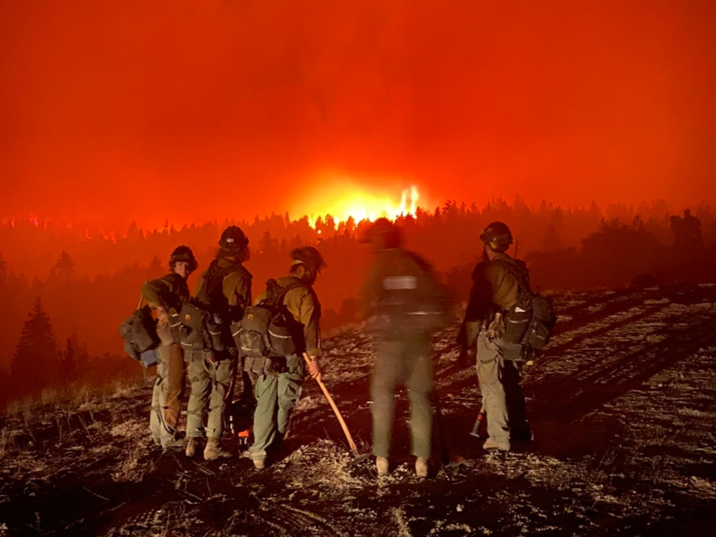 Wildland firefighters monitor a large blaze as they prepare to ‘spike out’ - spend the night under tarp without camping gear