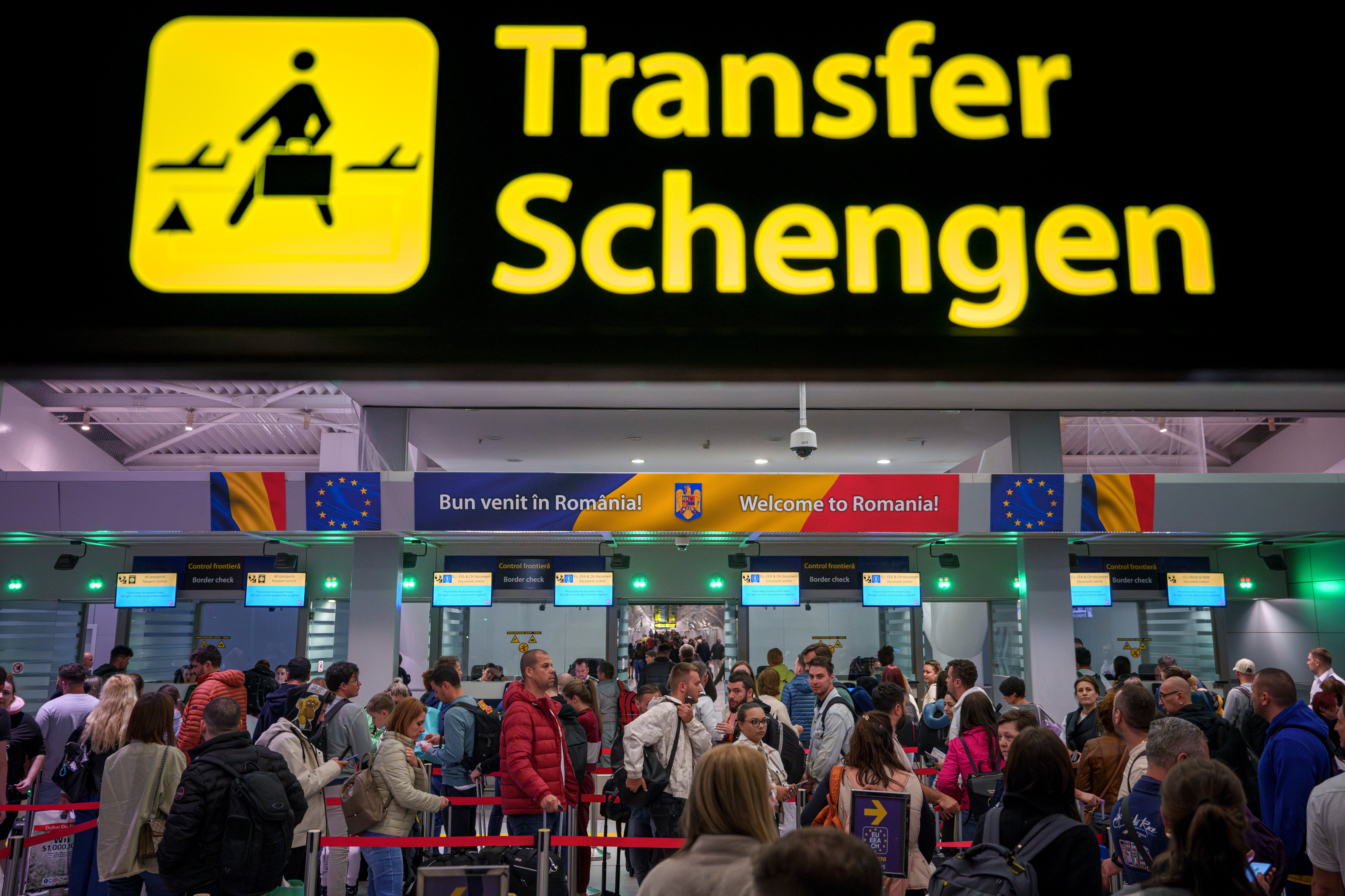 Passengers arriving at the Henri Coanda International Airport pass under a Schengen Information sign