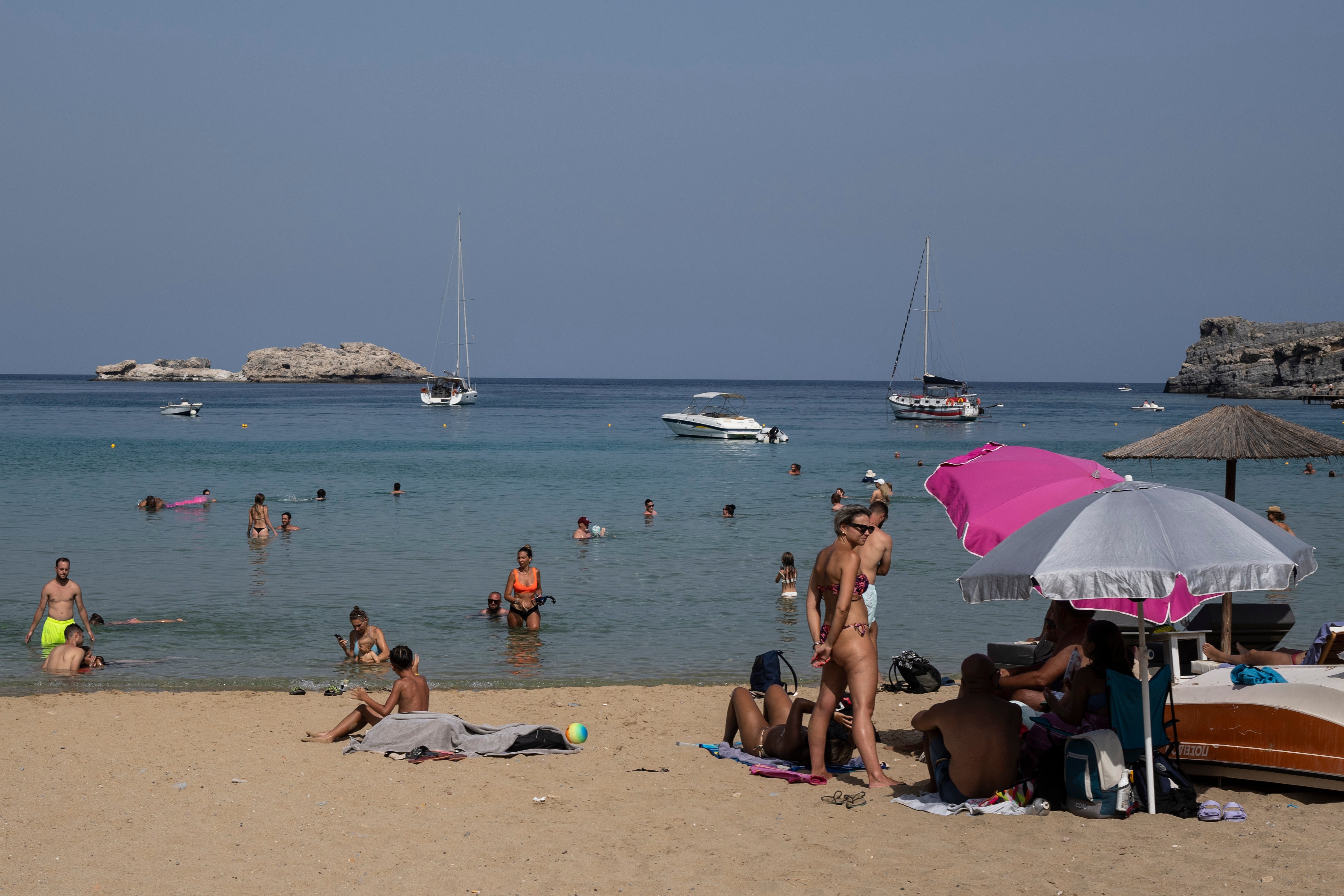 Tourists enjoy the beach and the sea in Lindos, on the Aegean Sea island of Rhodes