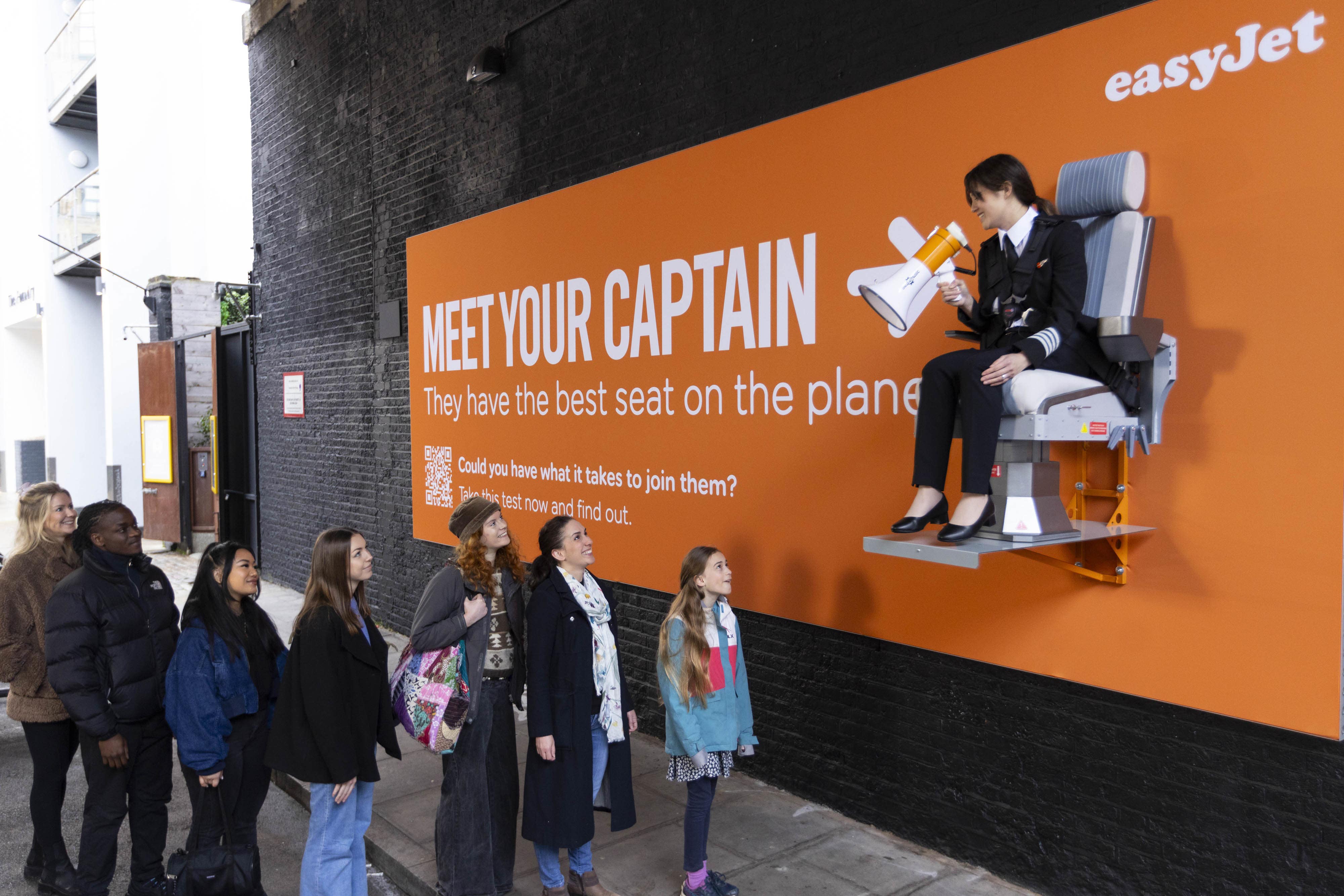 Pilot Sarah Ackerley sits on an interactive billboard in London at the launch of an easyJet campaign (David Parry/PA)