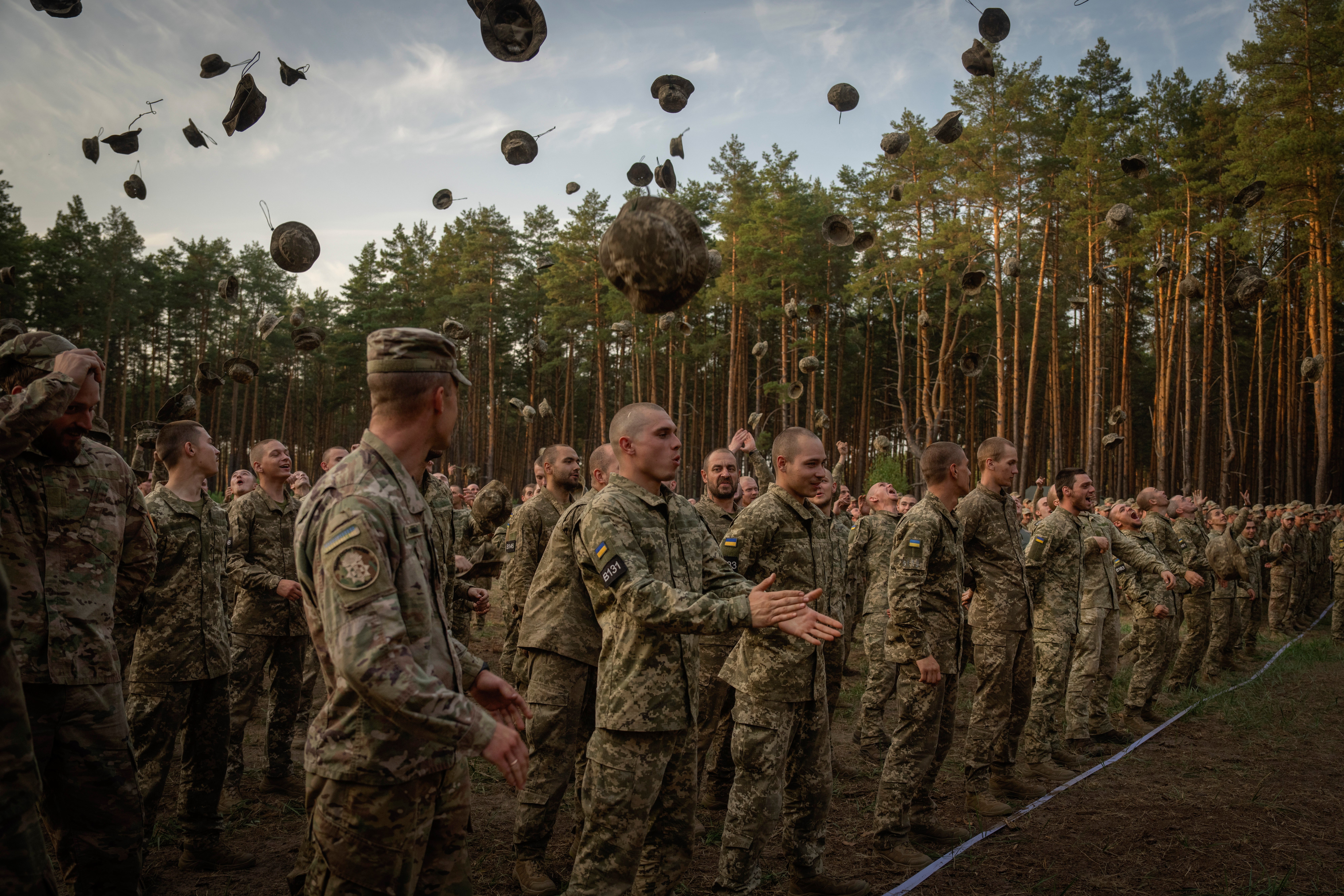 Newly recruited soldiers shout slogans as they celebrate the end of their training at a military base close to Kyiv, Ukraine