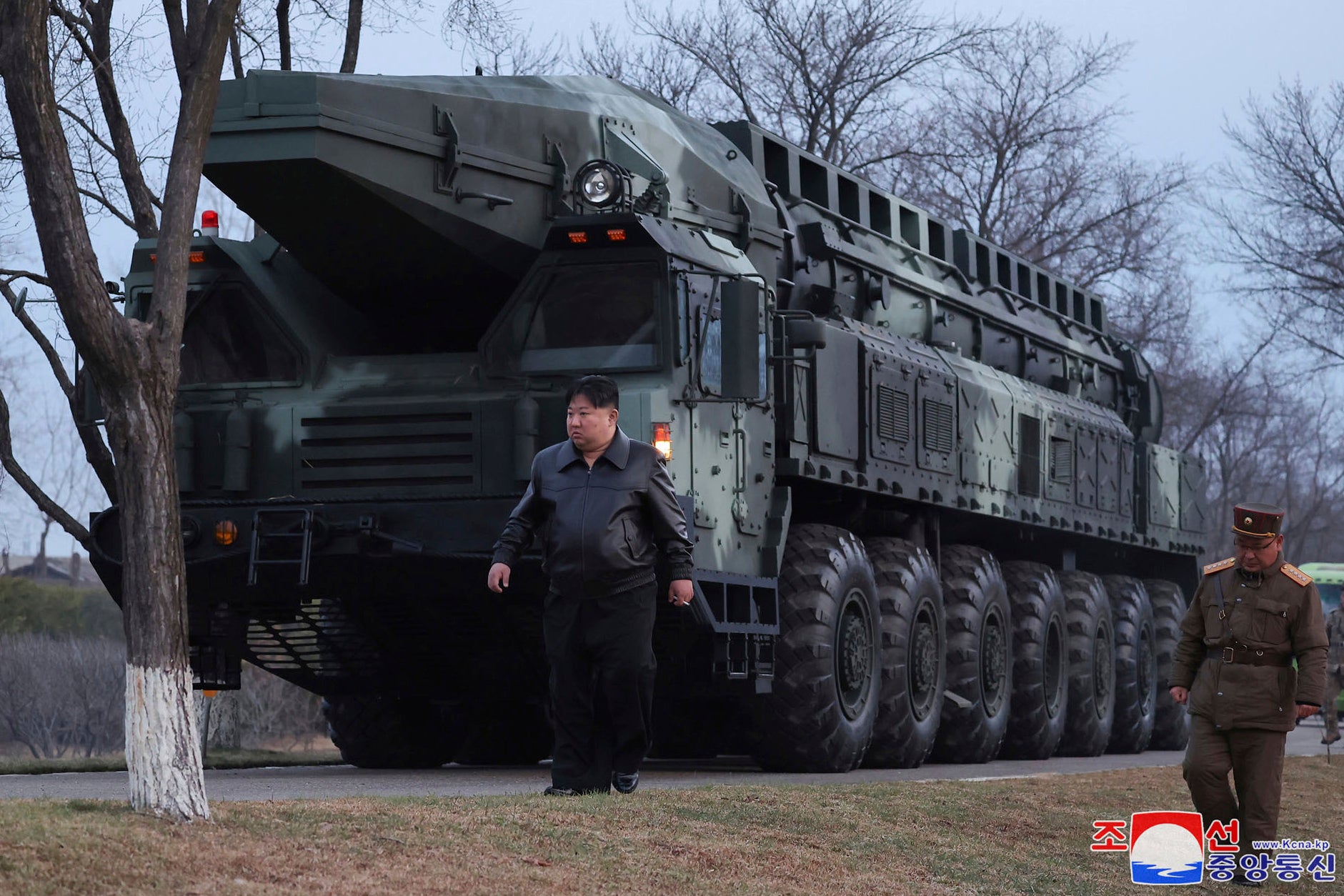 File: North Korean leader Kim Jong-un, center, walks by a missile launcher