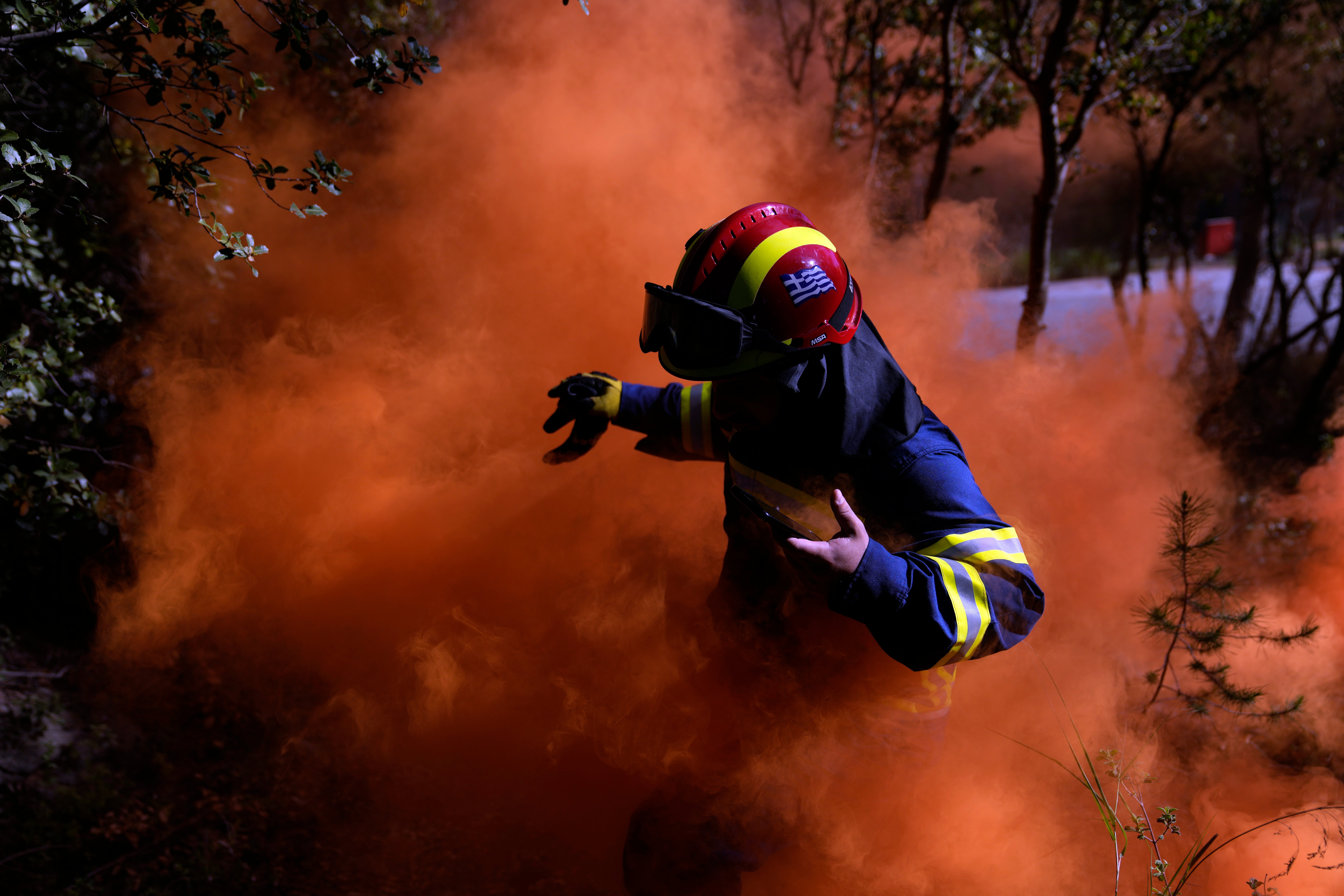 A firefighter leaves the area after lighting a smoke flare during a preparedness drill at Glyka Nera, in northeastern Athens