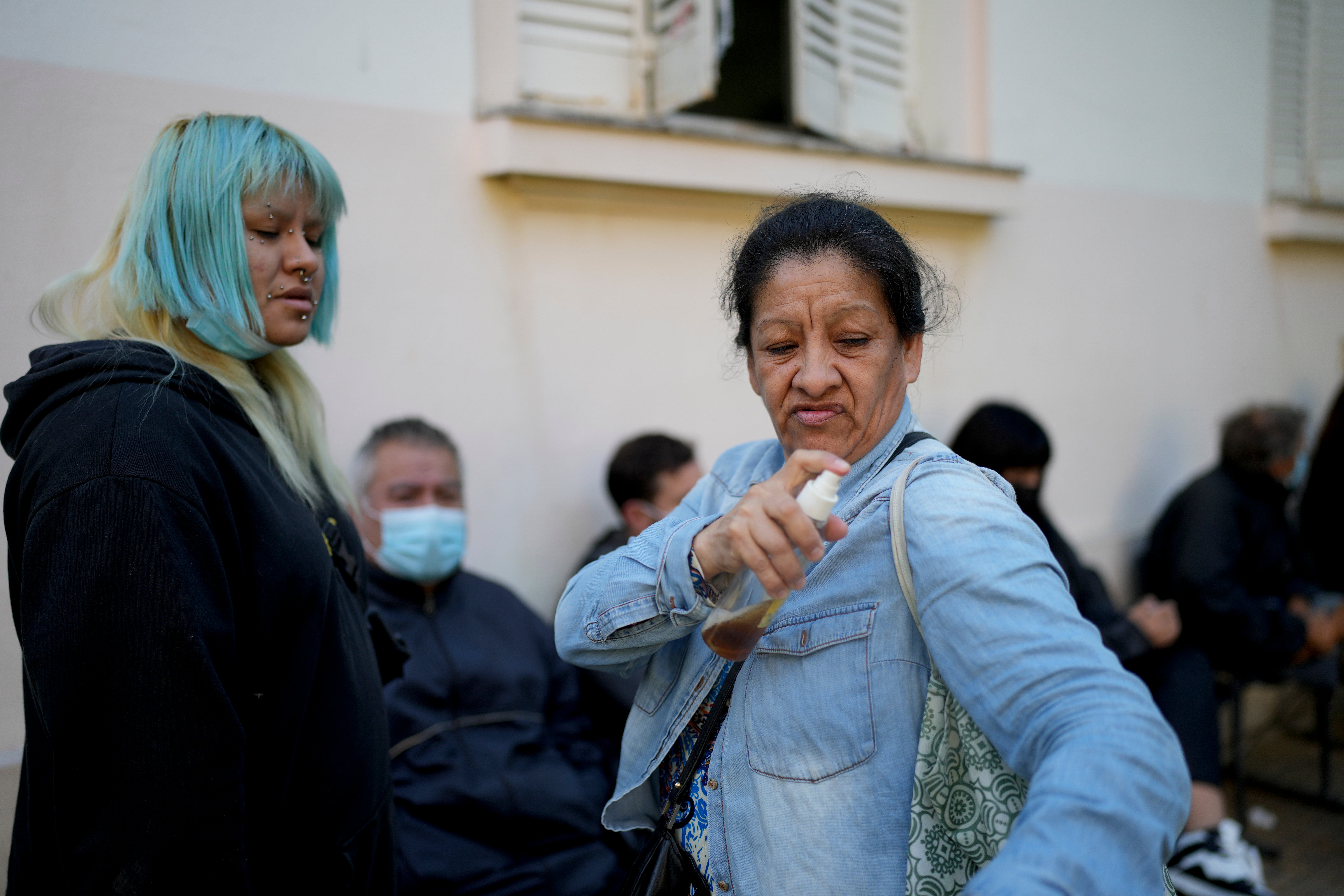 A woman sprays herself with a makeshift mosquito repellant of vanilla and water as she waits to be attended at a hospital