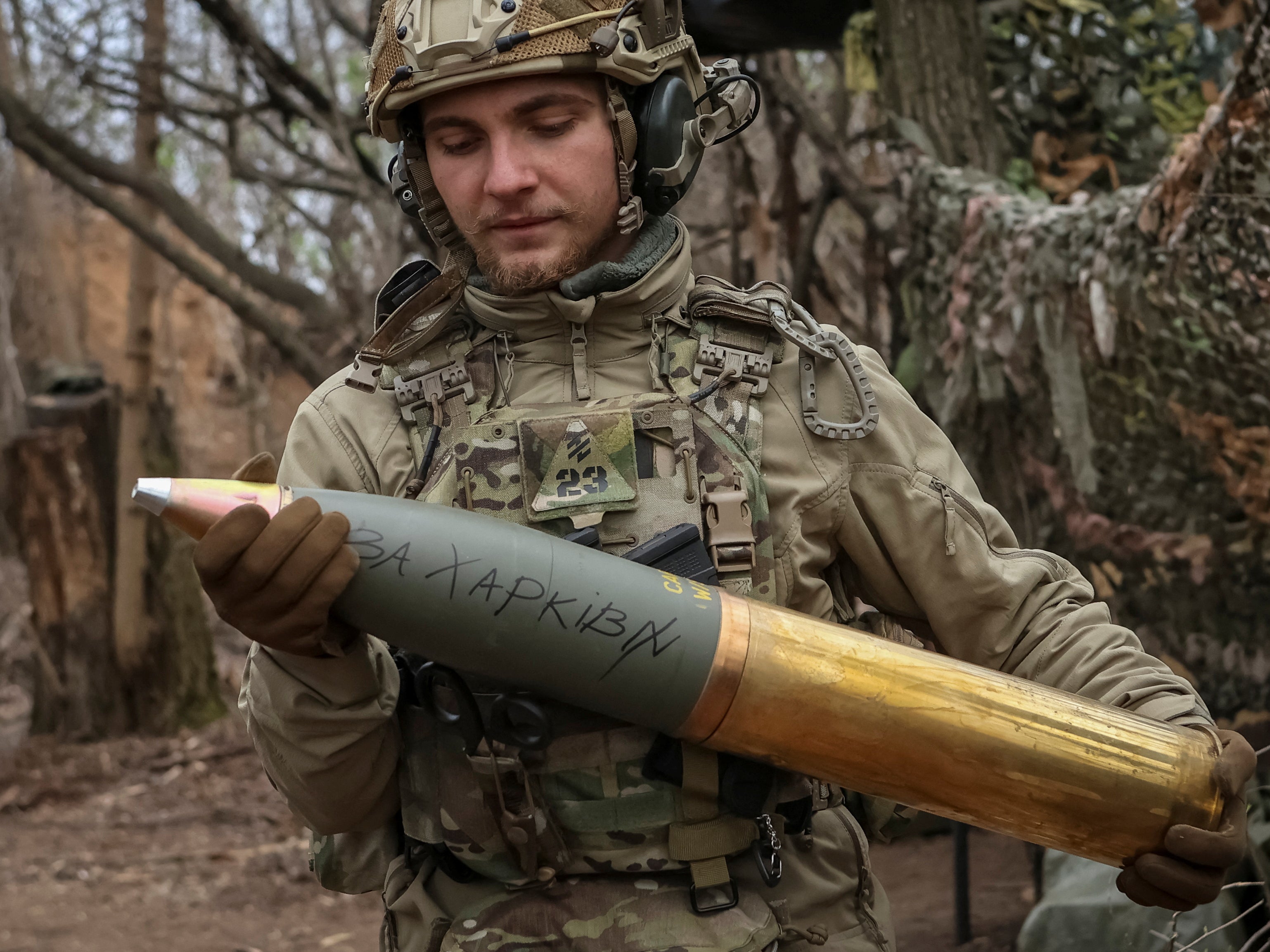 A Ukrainian serviceman prepares a shell with the inscription ‘for Kharkiv’