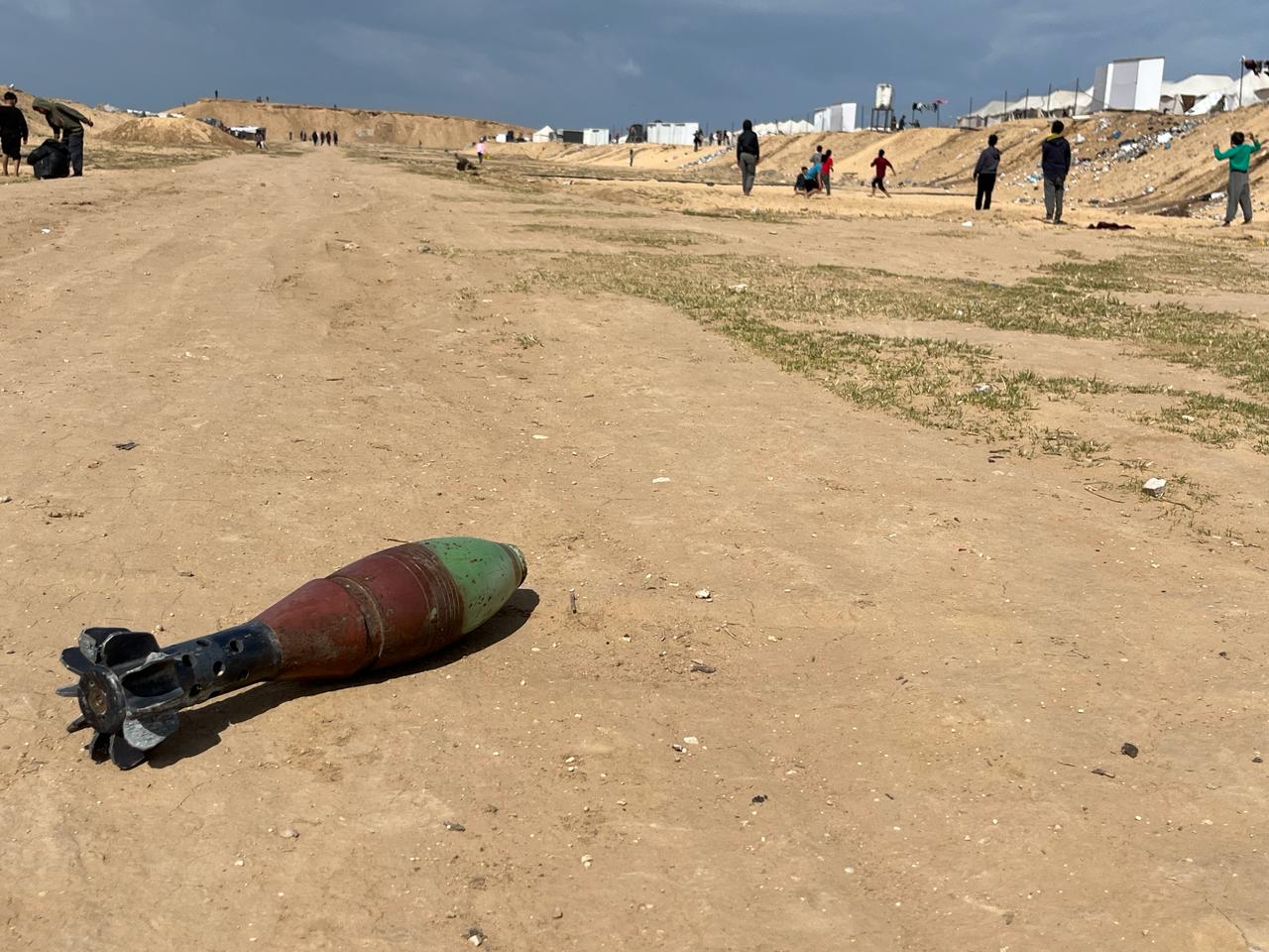 An exploded mortar bomb in Gaza, with young children not far away from the weapon