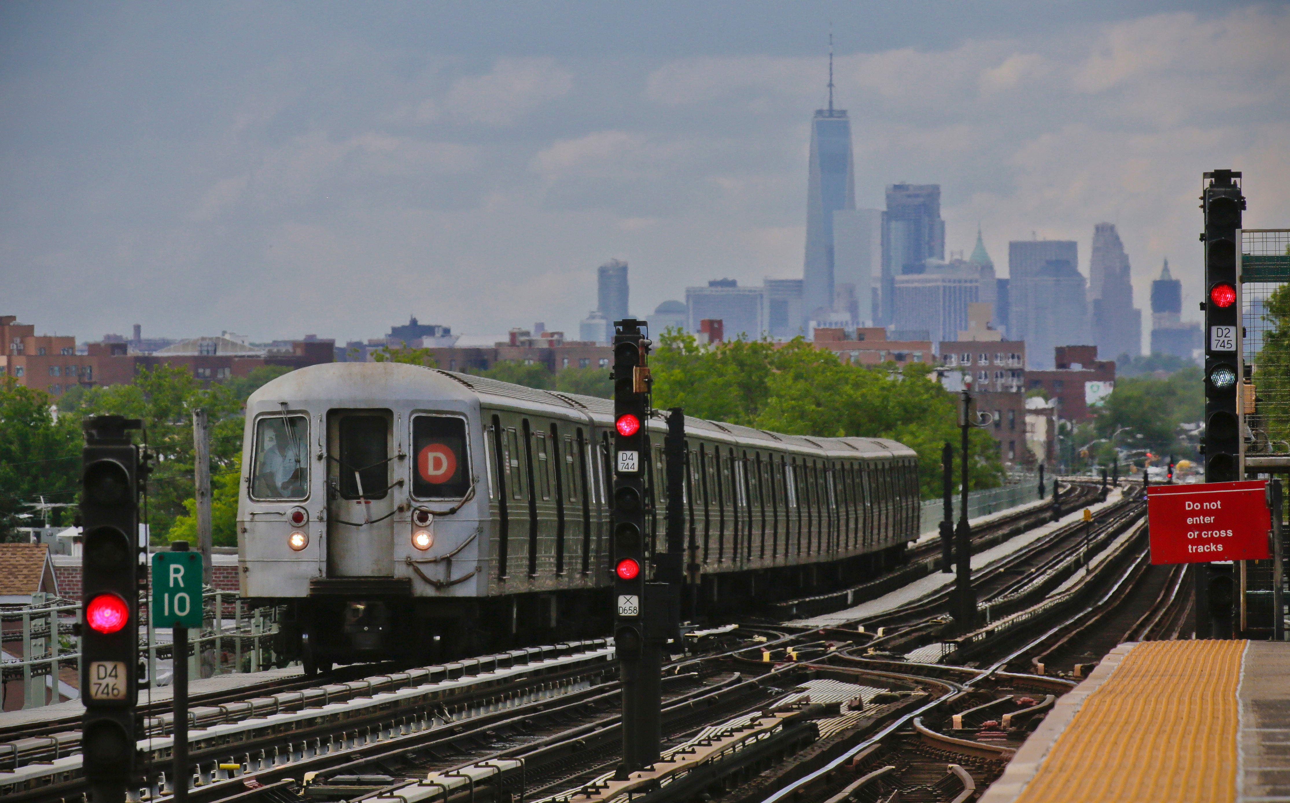 A subway approaches an above ground station in the Brooklyn borough of New York with the New York City skyline in the background, June 21, 2017