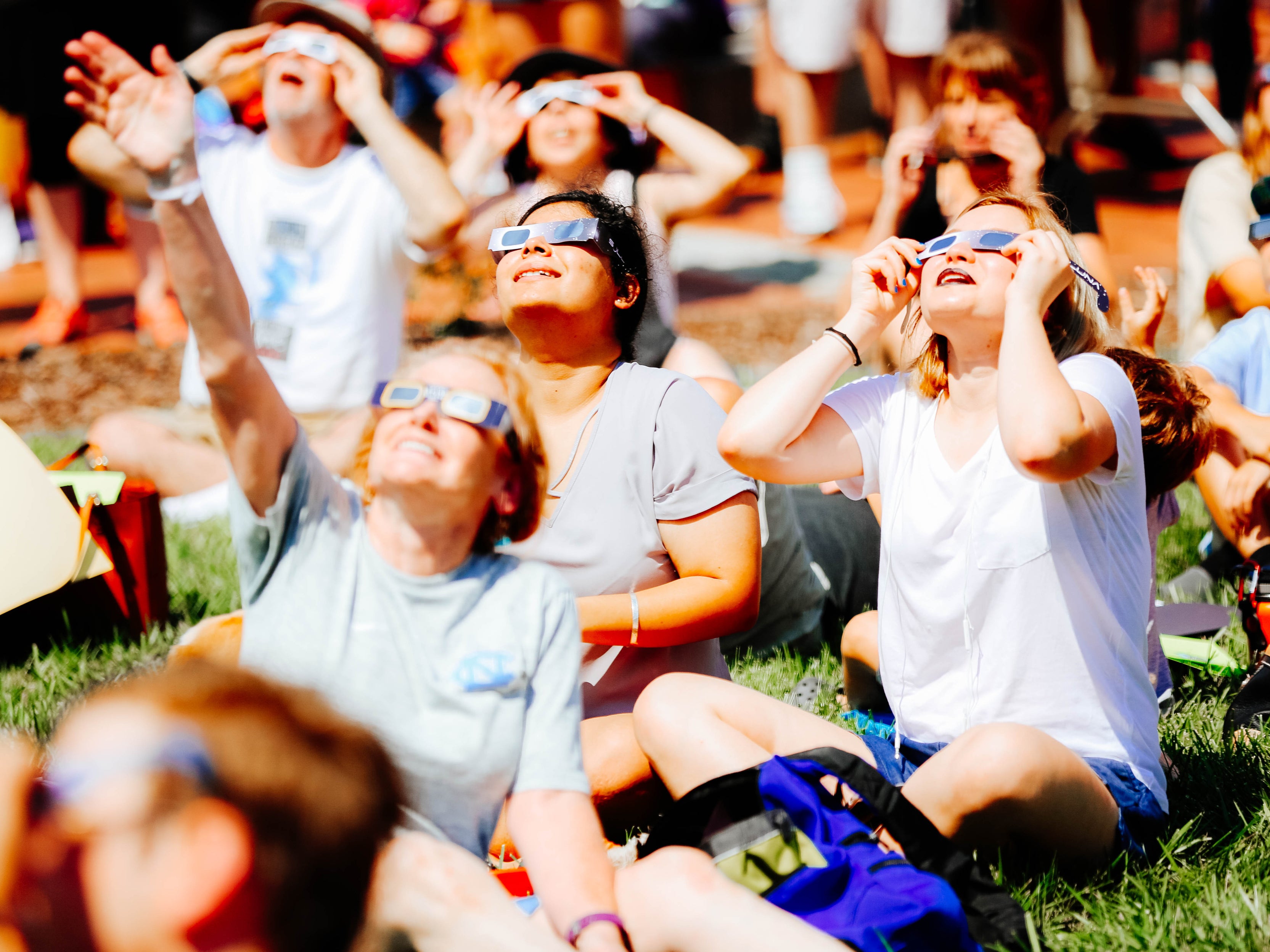 Solar eclipse spectators sitting in the park wearing the proper eclipse glasses