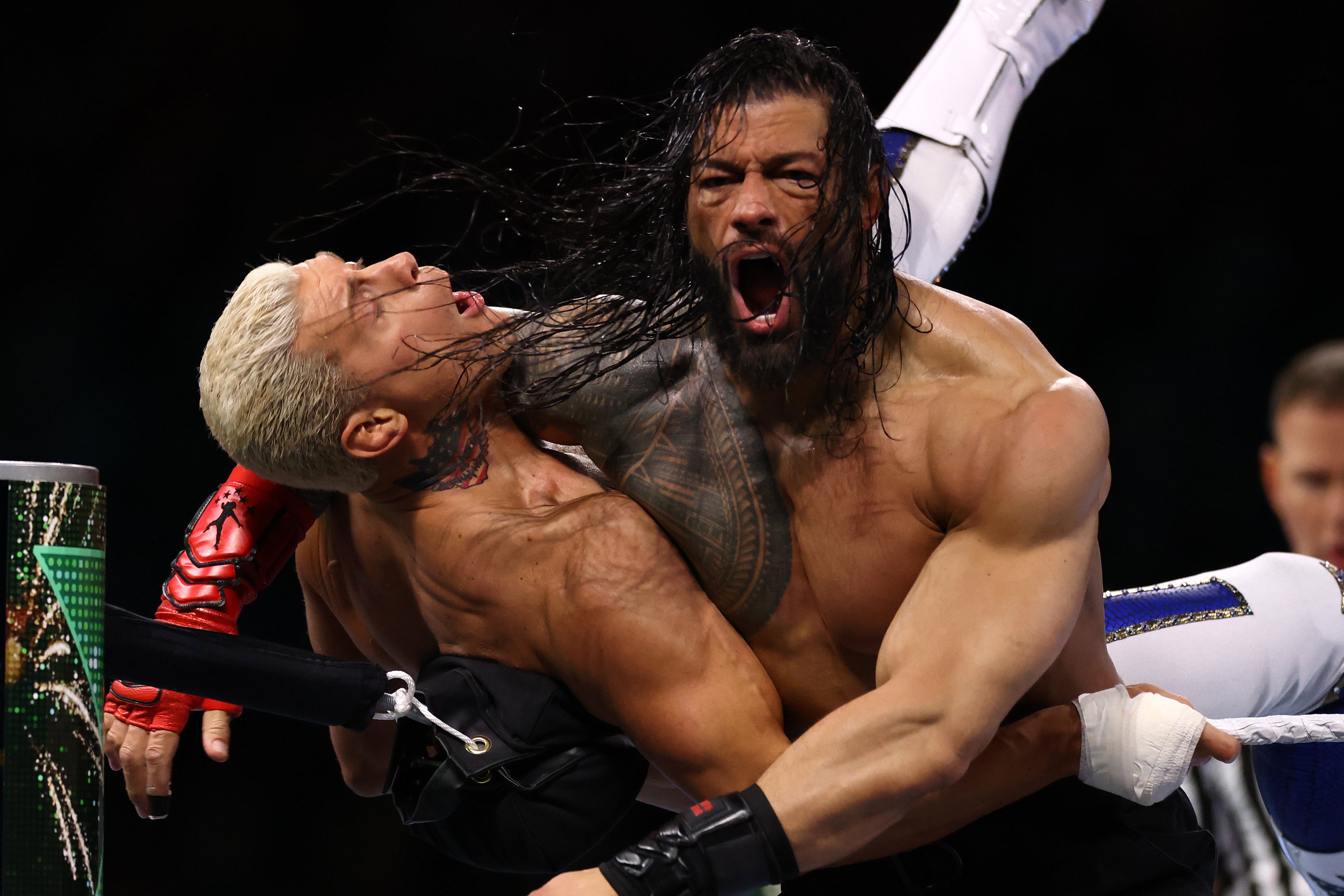 Roman Reigns (right) attacking Cody Rhodes in the corner of the ring