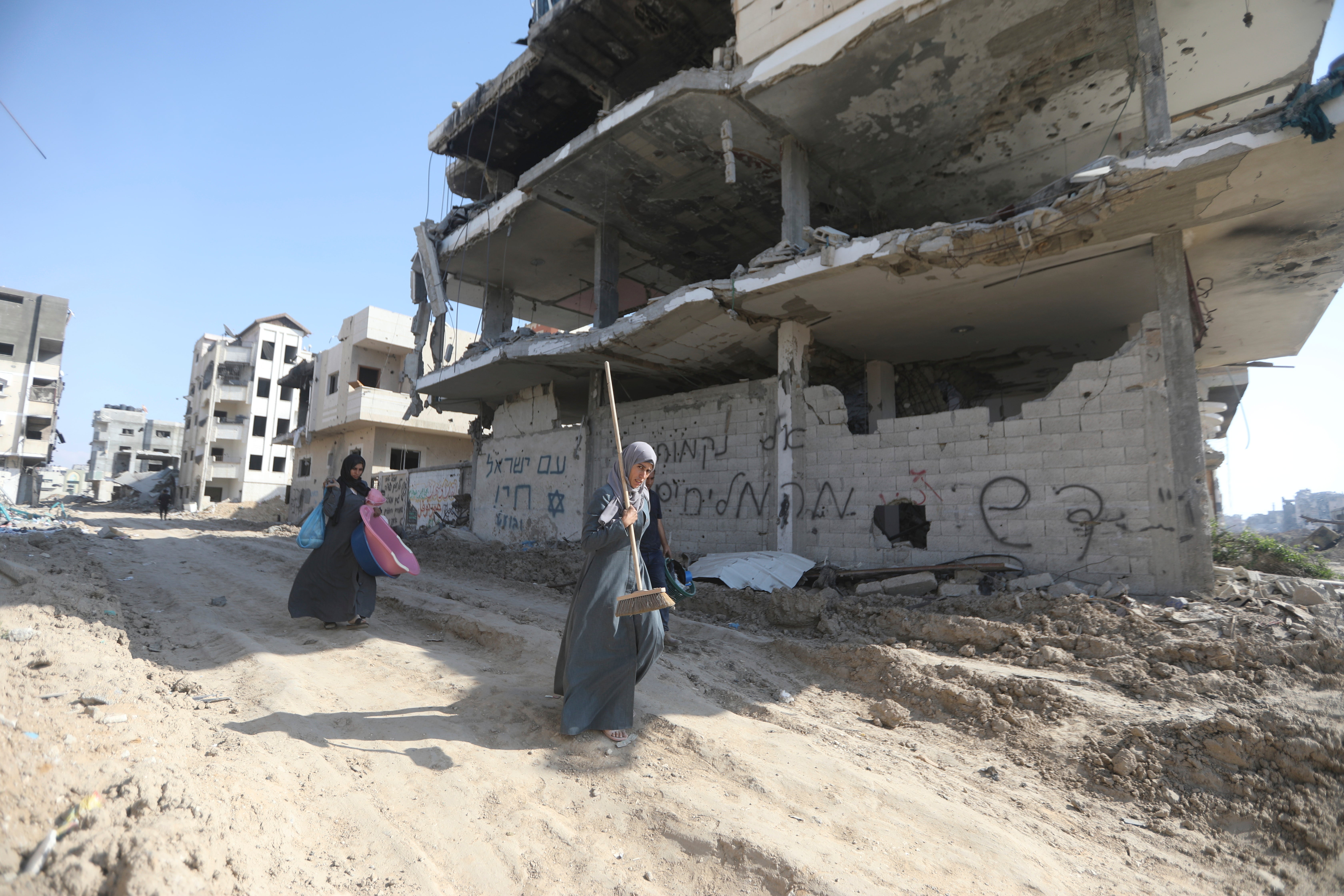 Palestinians walk through the destruction left by the Israeli air and ground offensive