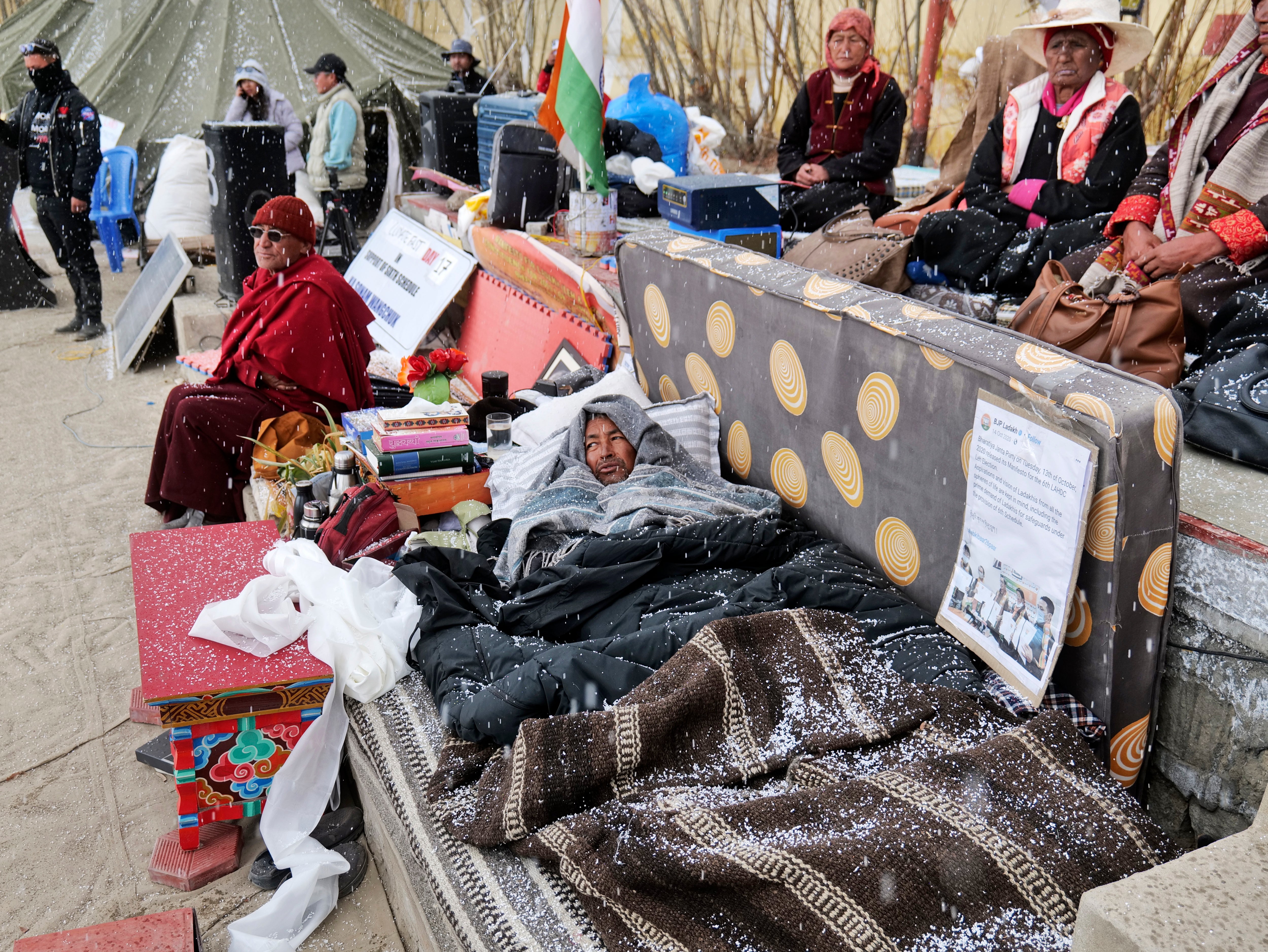 Sonam Wangchuk, lying under blankets, is surrounded by supporters during his hunger strike