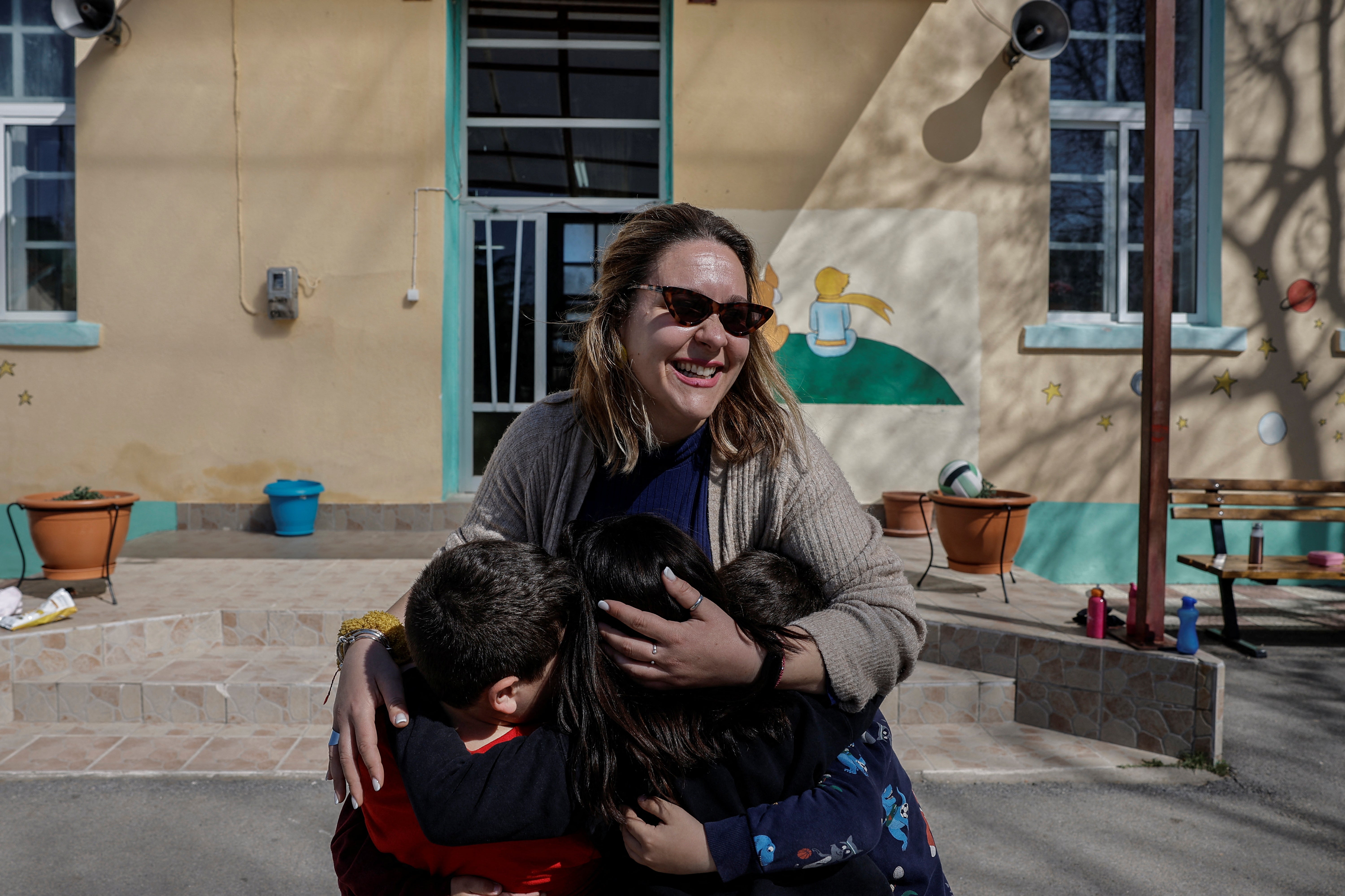 Nektaria Mouropoulou, 34, a first-grade teacher, embraces her students in the primary school of Dikaia village