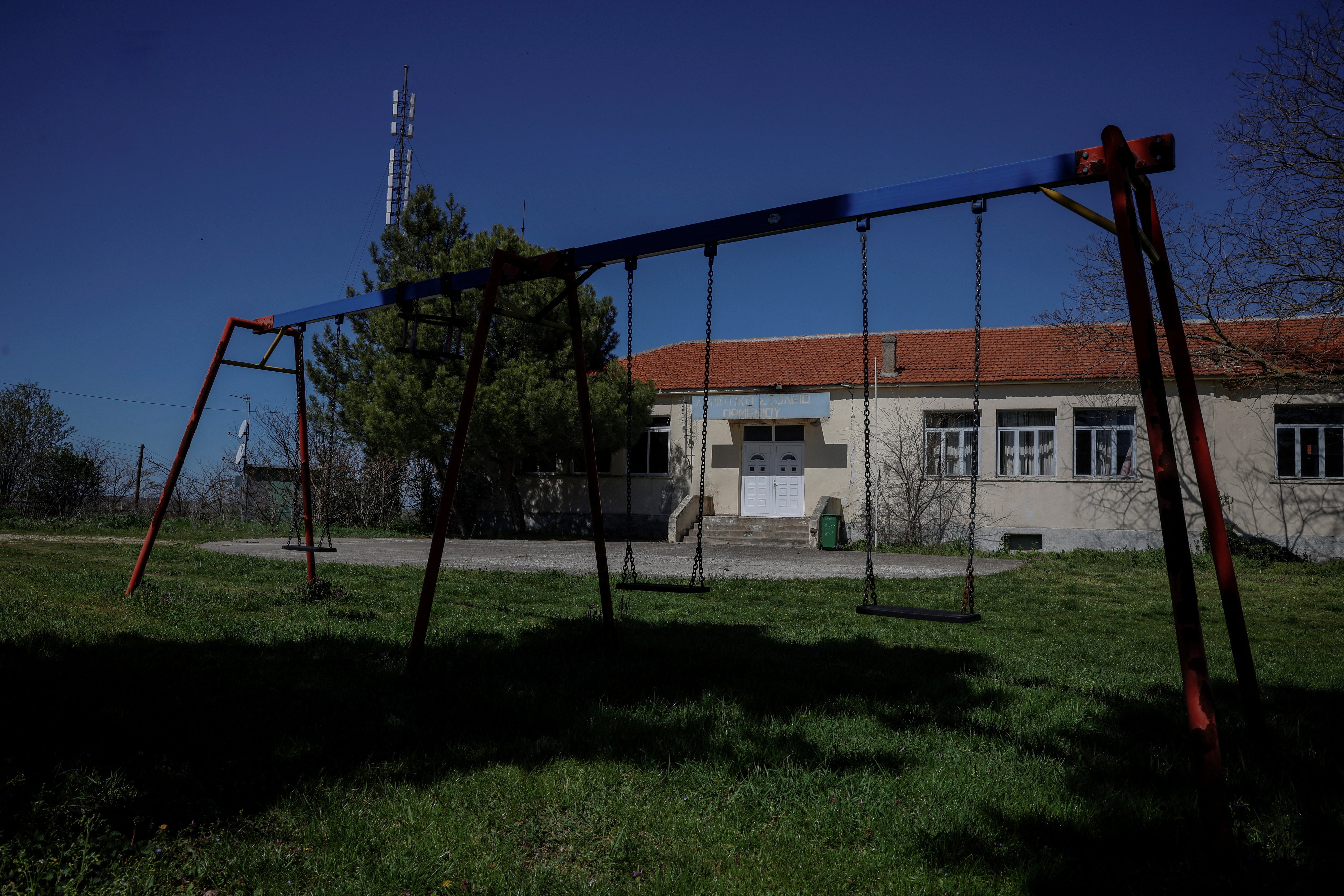 Swings are seen outside a closed school in the village of Ormenio, Greece