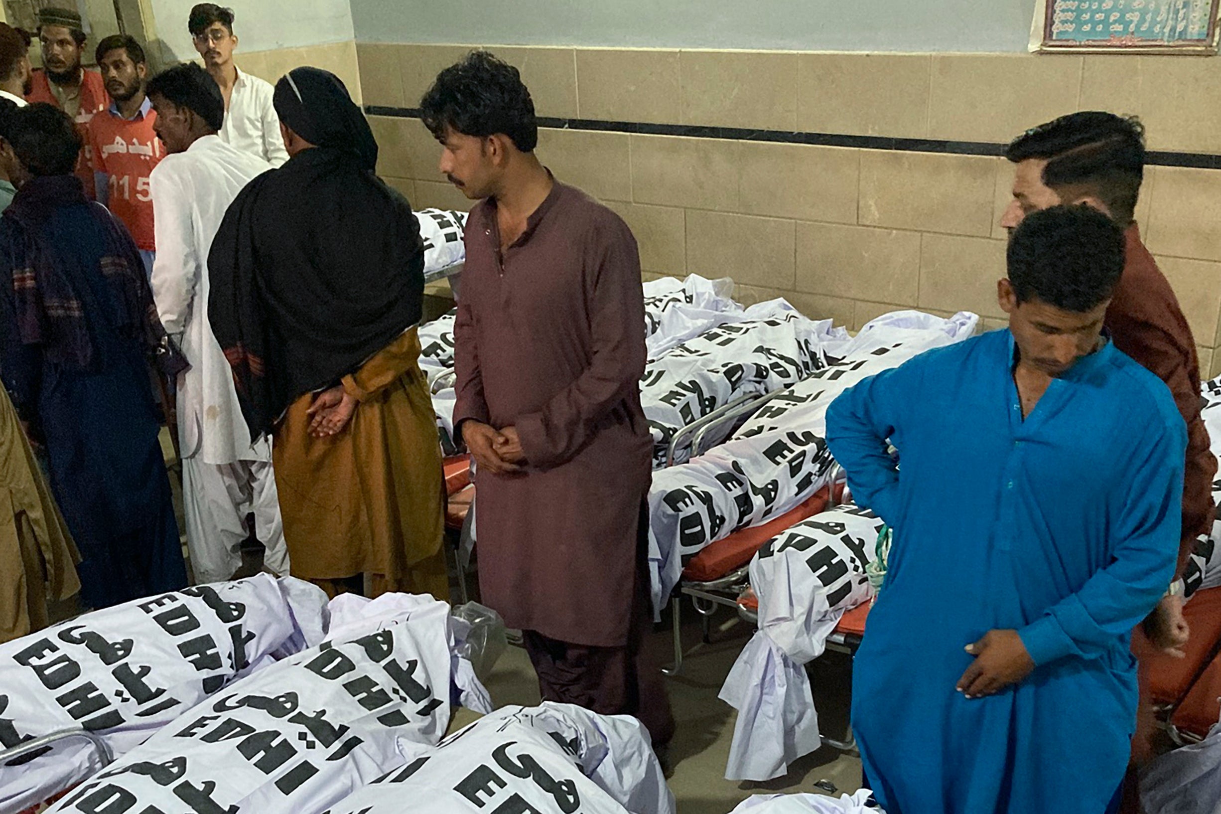 People wait to collect the body of their relative who were died in a bus crash, at a morgue in Karachi, Pakistan