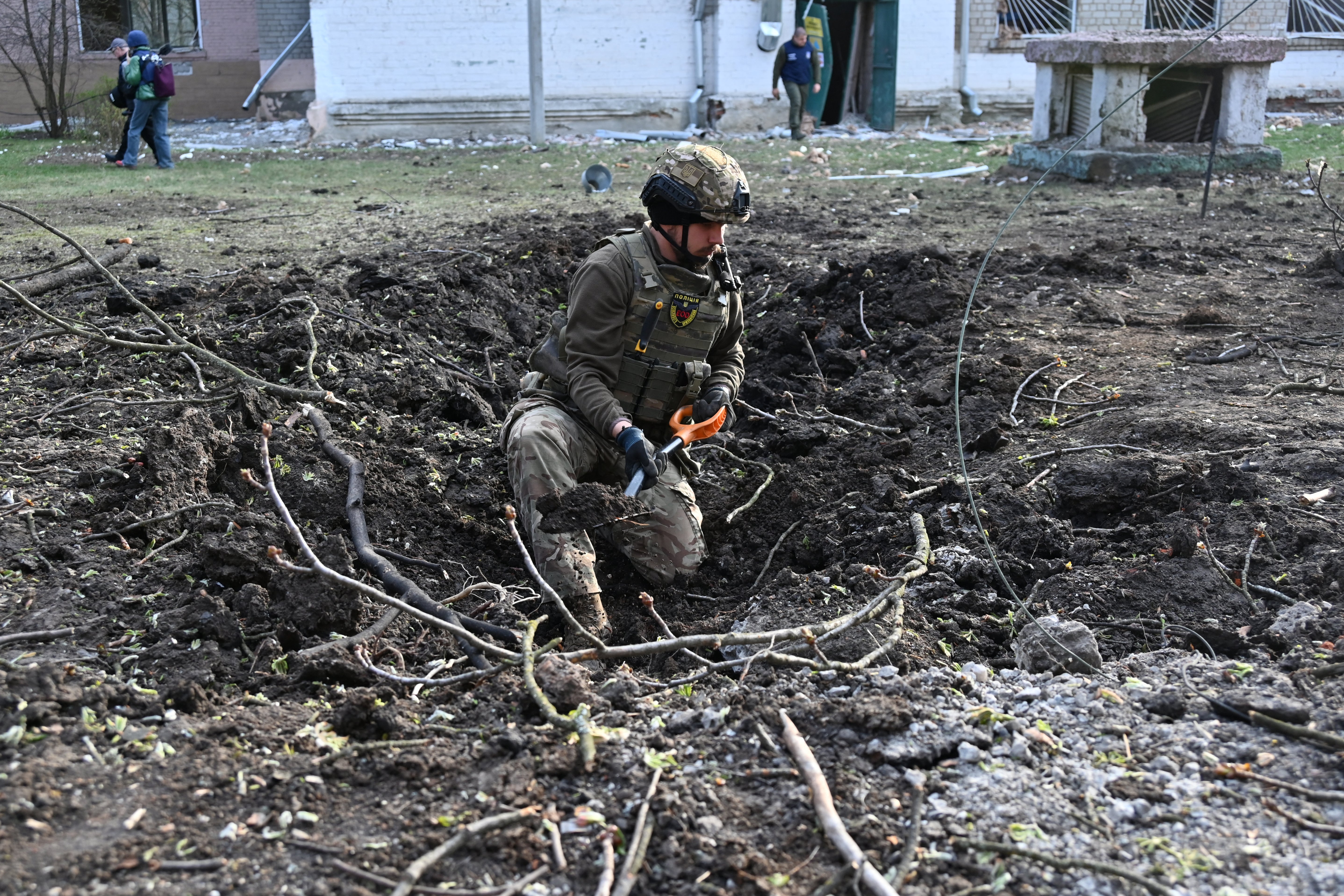 A Ukrainian explosive technician examines the site of a missile strike in Kharkiv