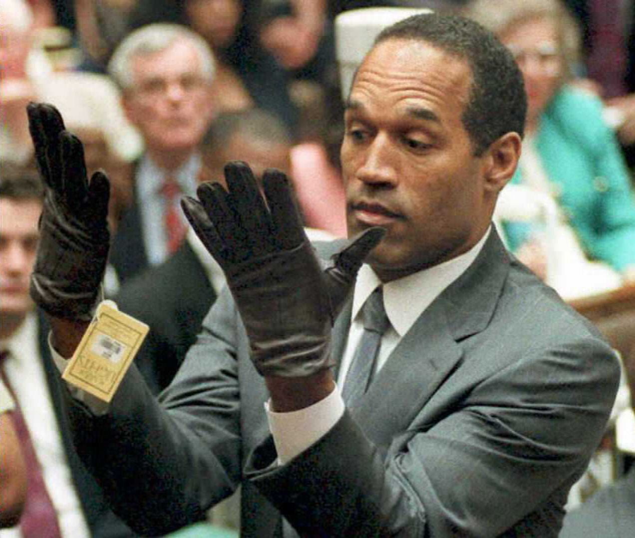 OJ Simpson looks at a new pair of Aris extra-large gloves that prosecutors had him put on 21 June 1995 during his double-murder trial in Los Angeles.