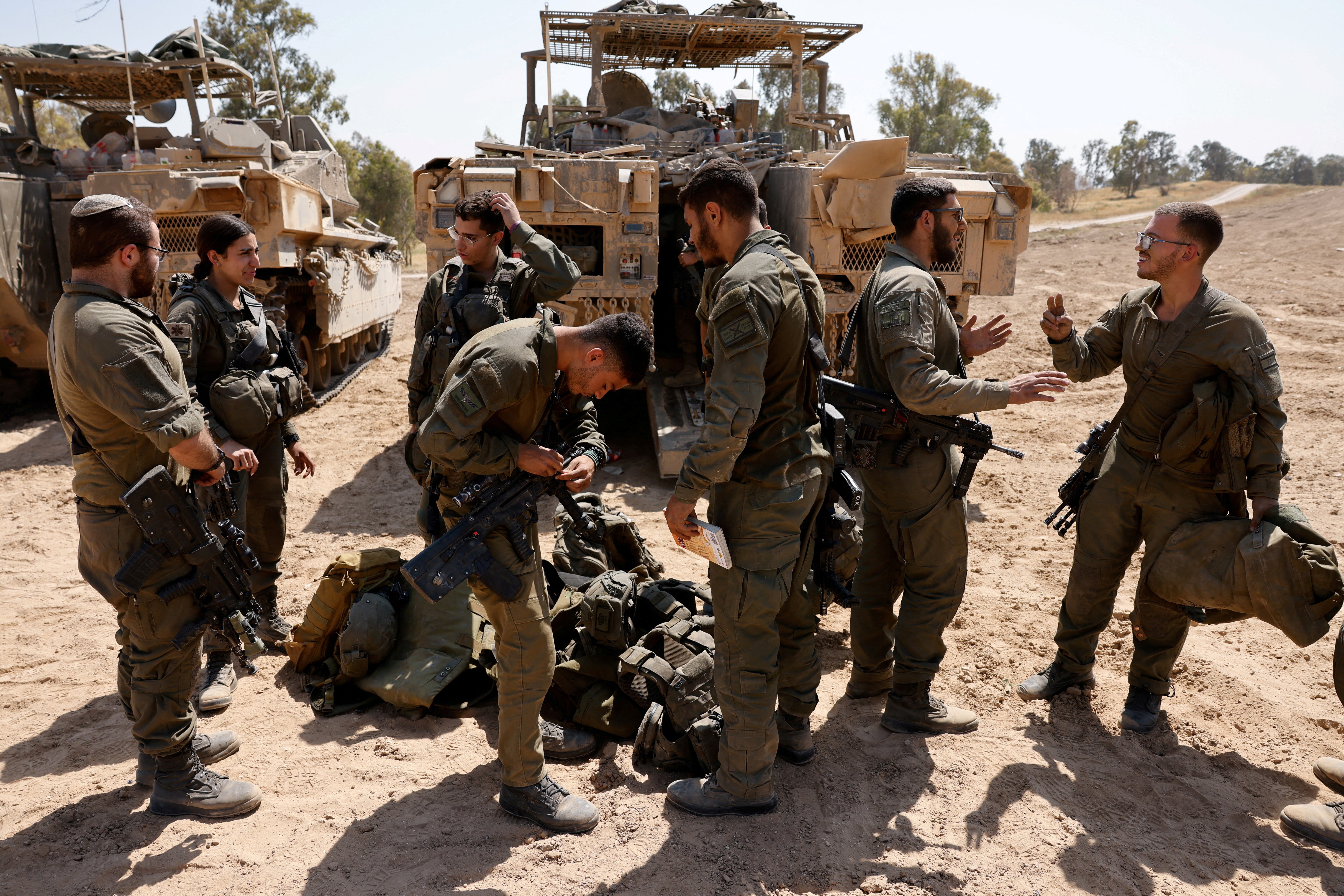 Israeli soldiers stand next to military vehicles, near the Israel-Gaza border