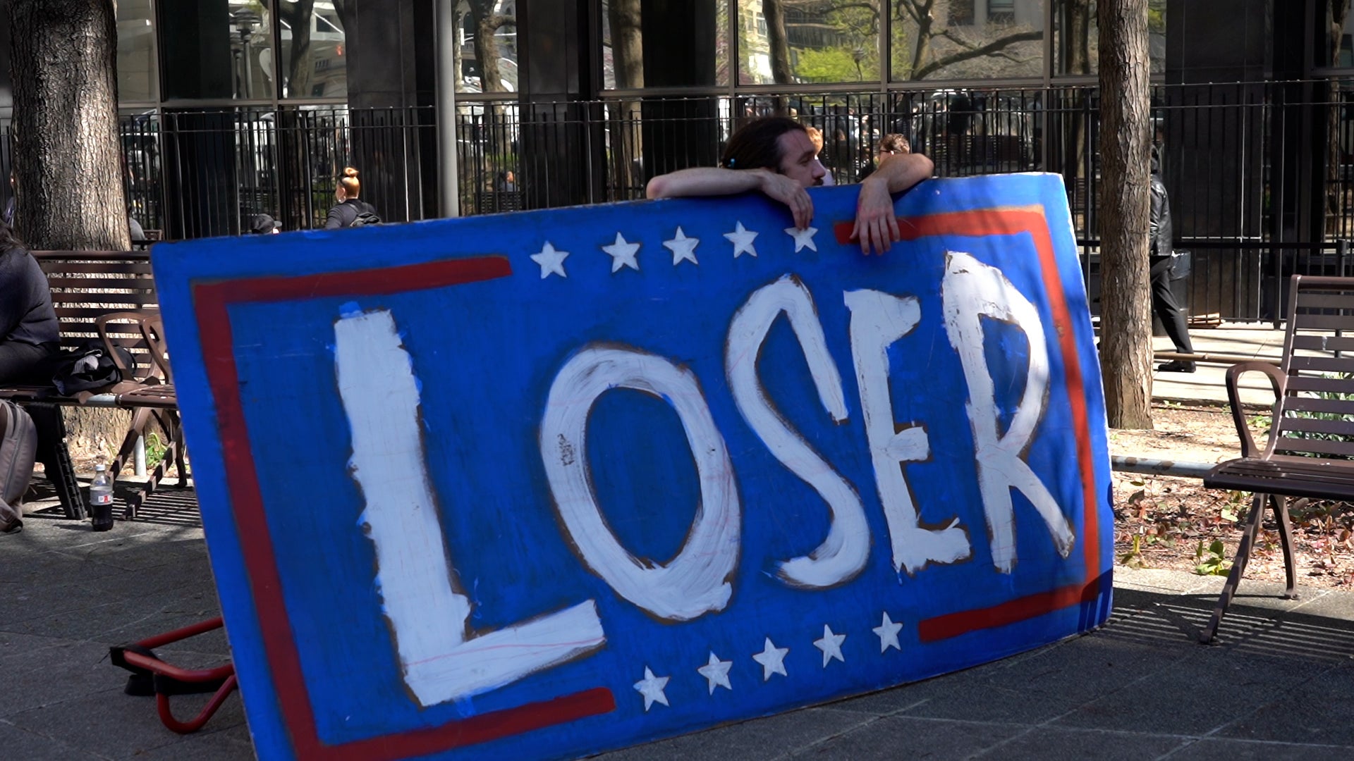 A man holds a protest sign outside of court as former president Donald Trump’s trial begins