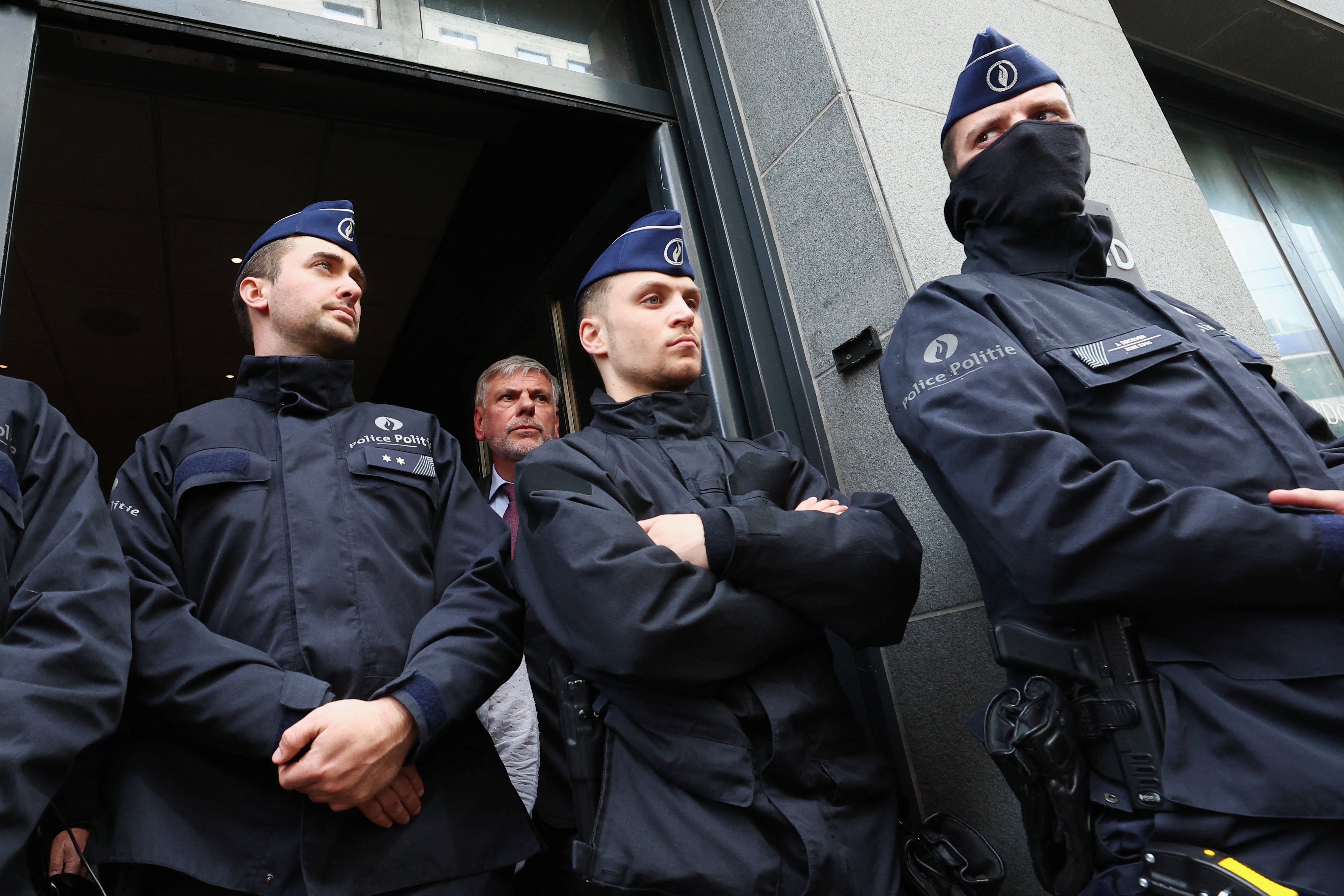 Far-right Flemish separatist party Vlaams Belang member Filip Dewinter stands behind police officers at the entrance