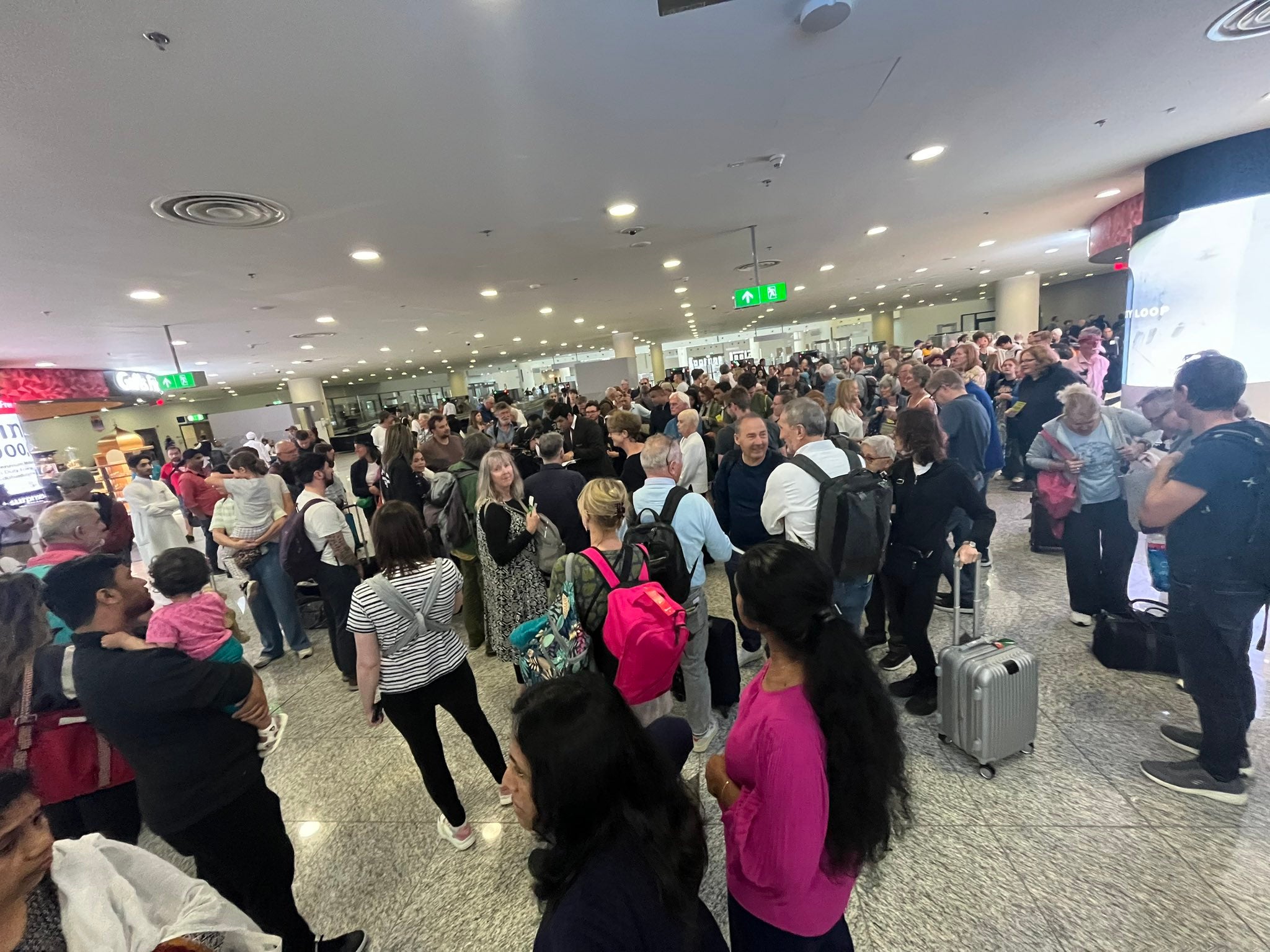 People listening to an Emirates member of staff (centre) whilst waiting at Dubai World Central airport, April 17, 2024