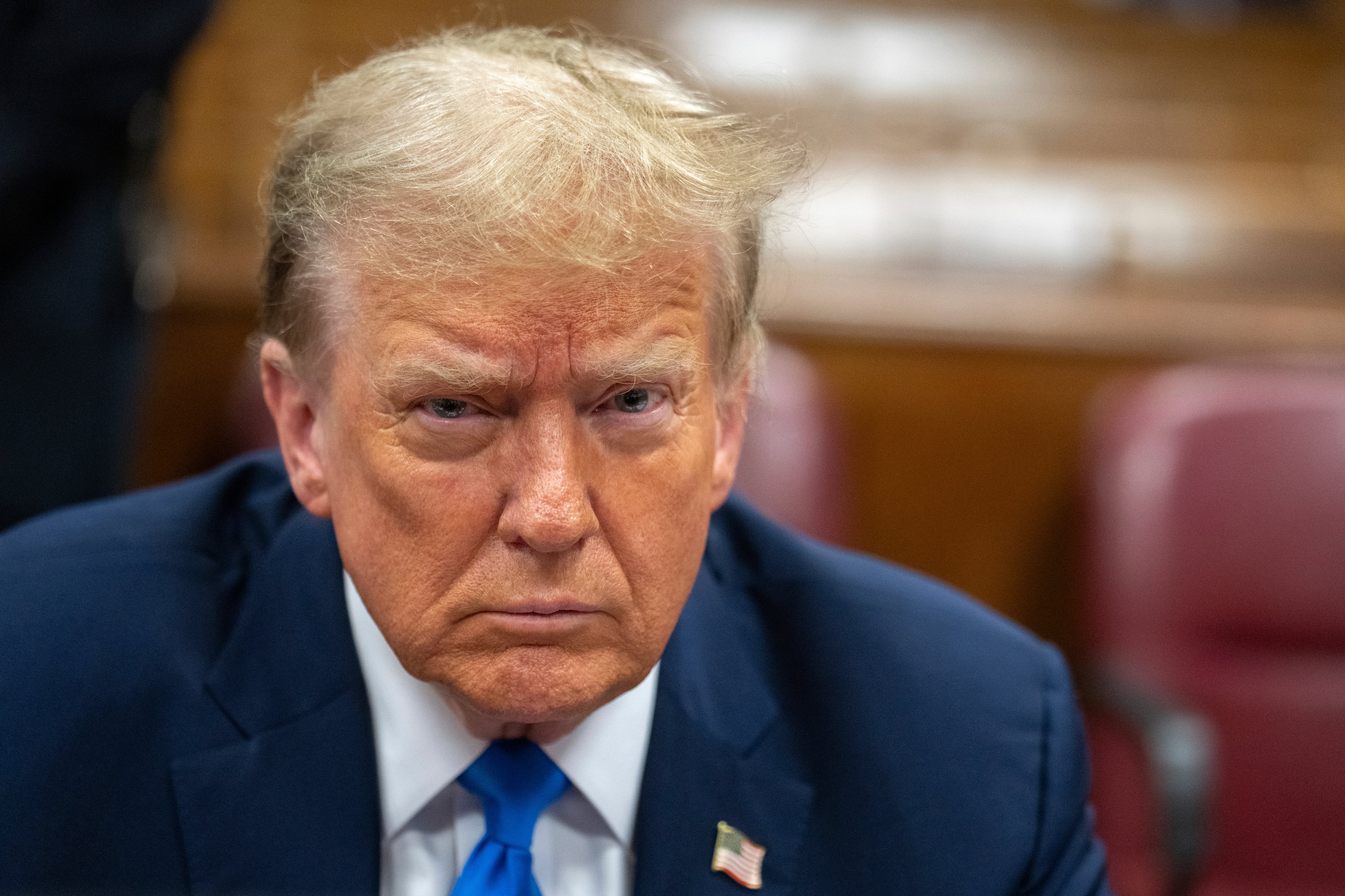 An angry-looking Mr Trump waits for the start of the third day of jury selection