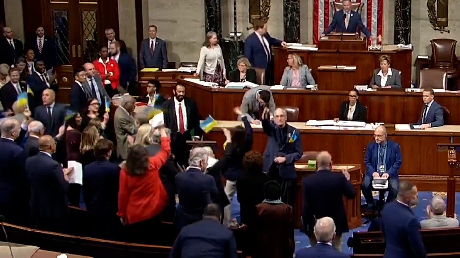 Representatives celebrate and wave flags after Congress passes Ukraine aid package (House TV/Reuters)