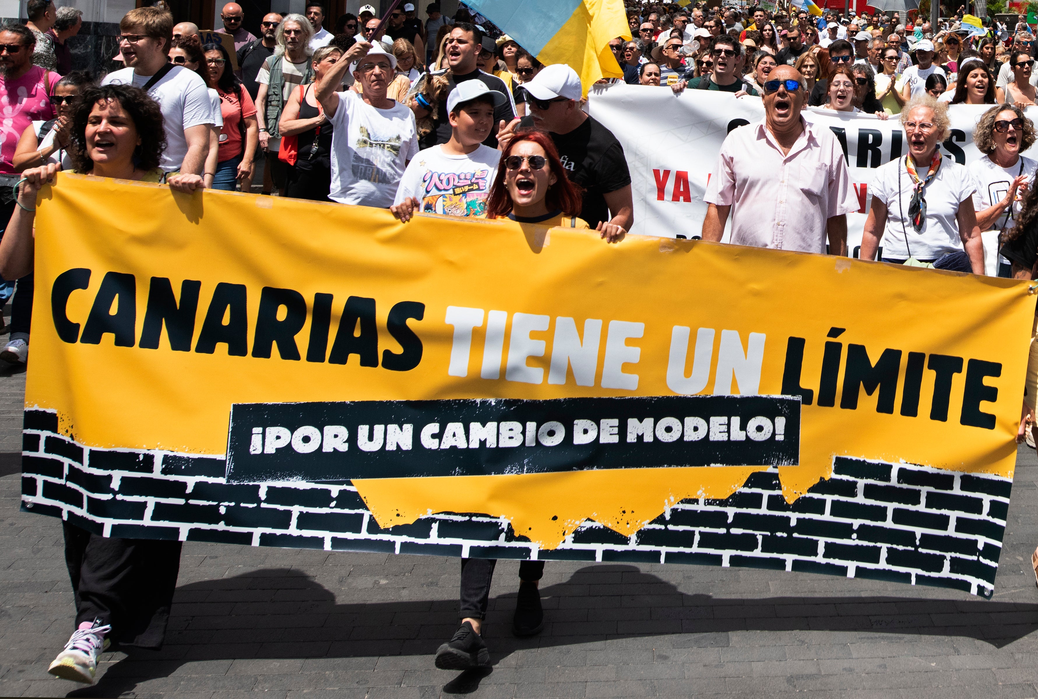 People march during a mass demonstration against tourism, which affects the local population with inaccessible housing among other things in Santa Cruz de Tenerife, Spain, on Saturday