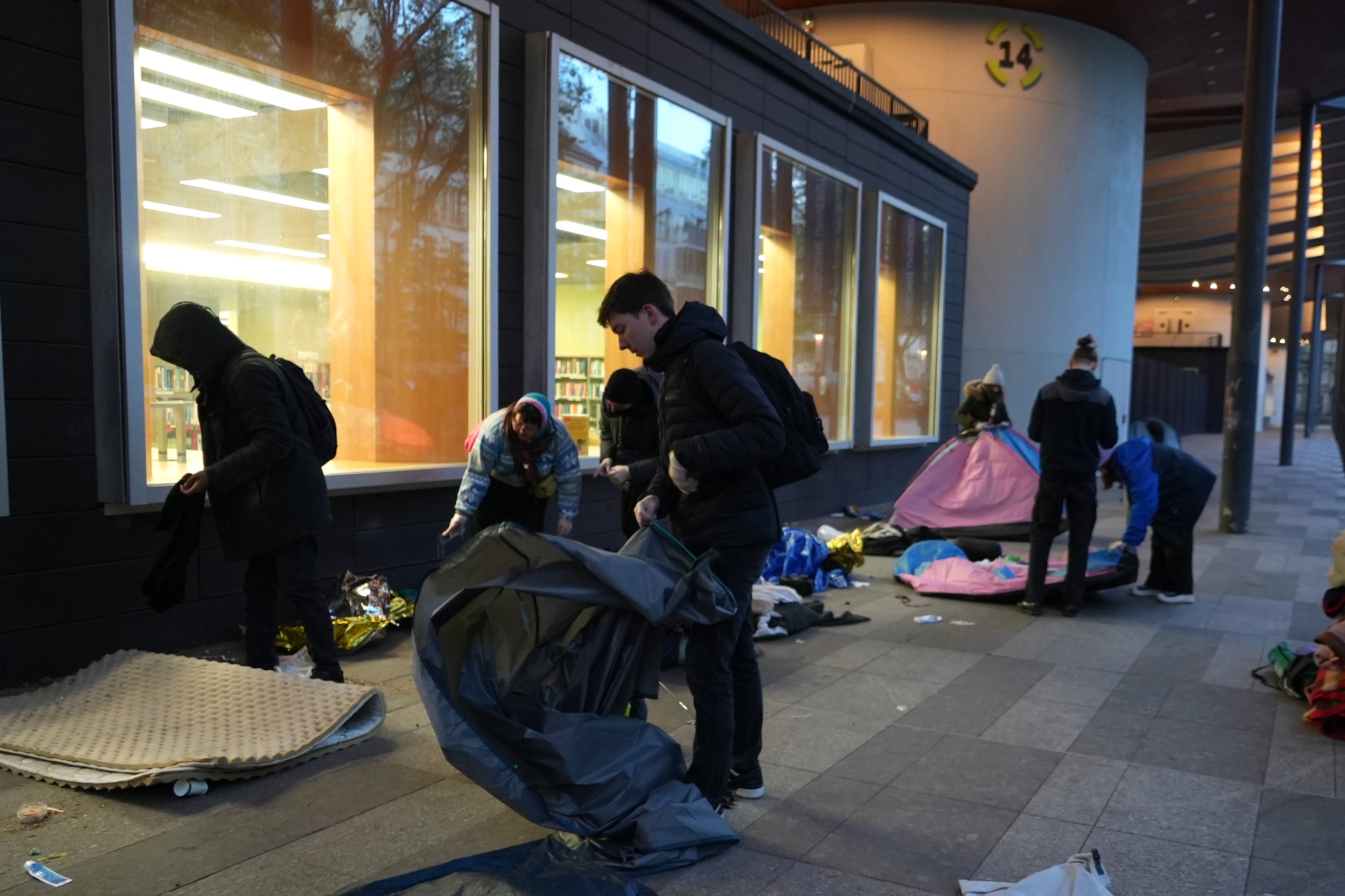 Activists help migrants to pack their belongings in a makeshift camp, early Tuesday, April 23, 2024 in Paris