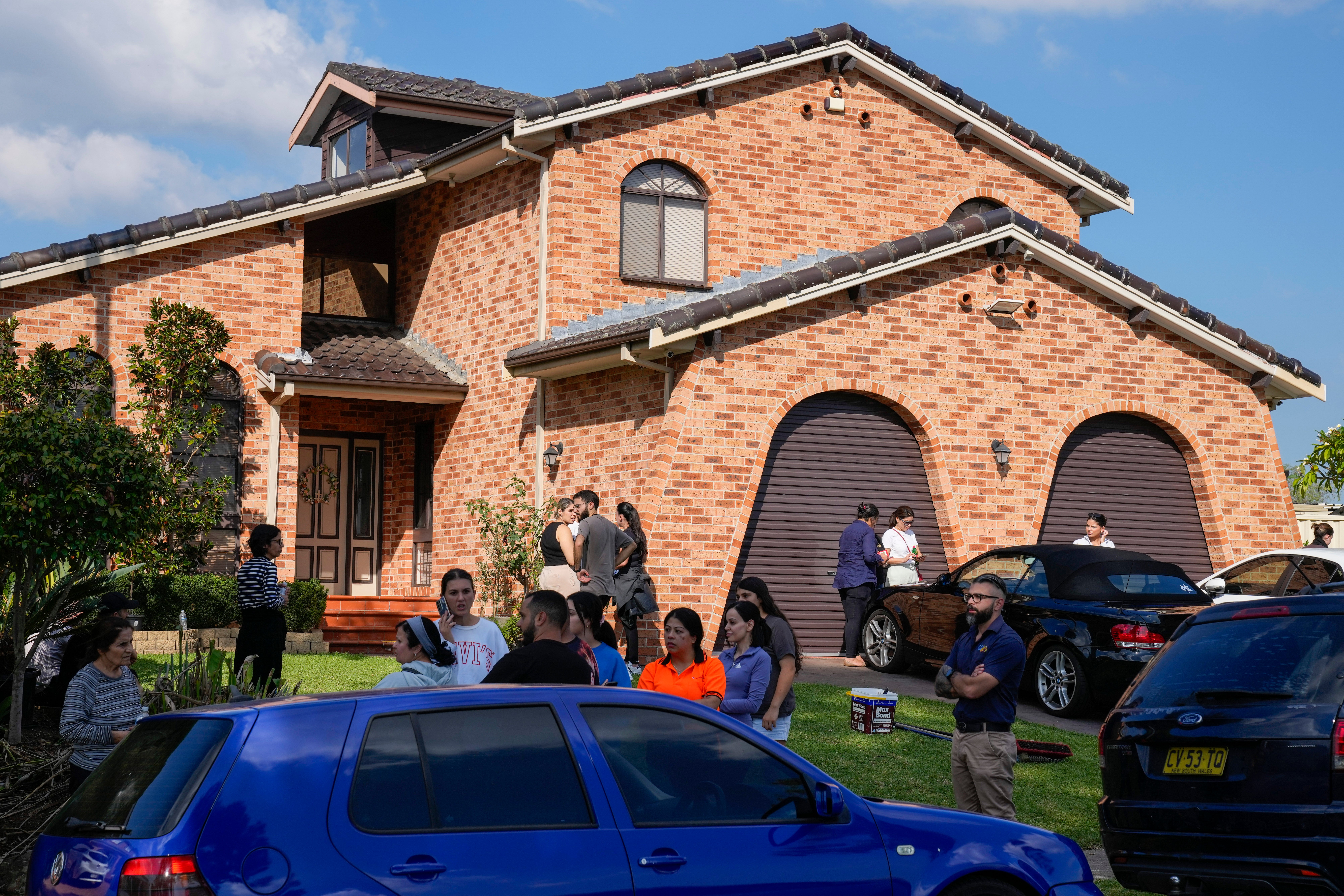 People stand outside a house across the road from the Christ the Good Shepherd church in suburban Wakely in western Sydney