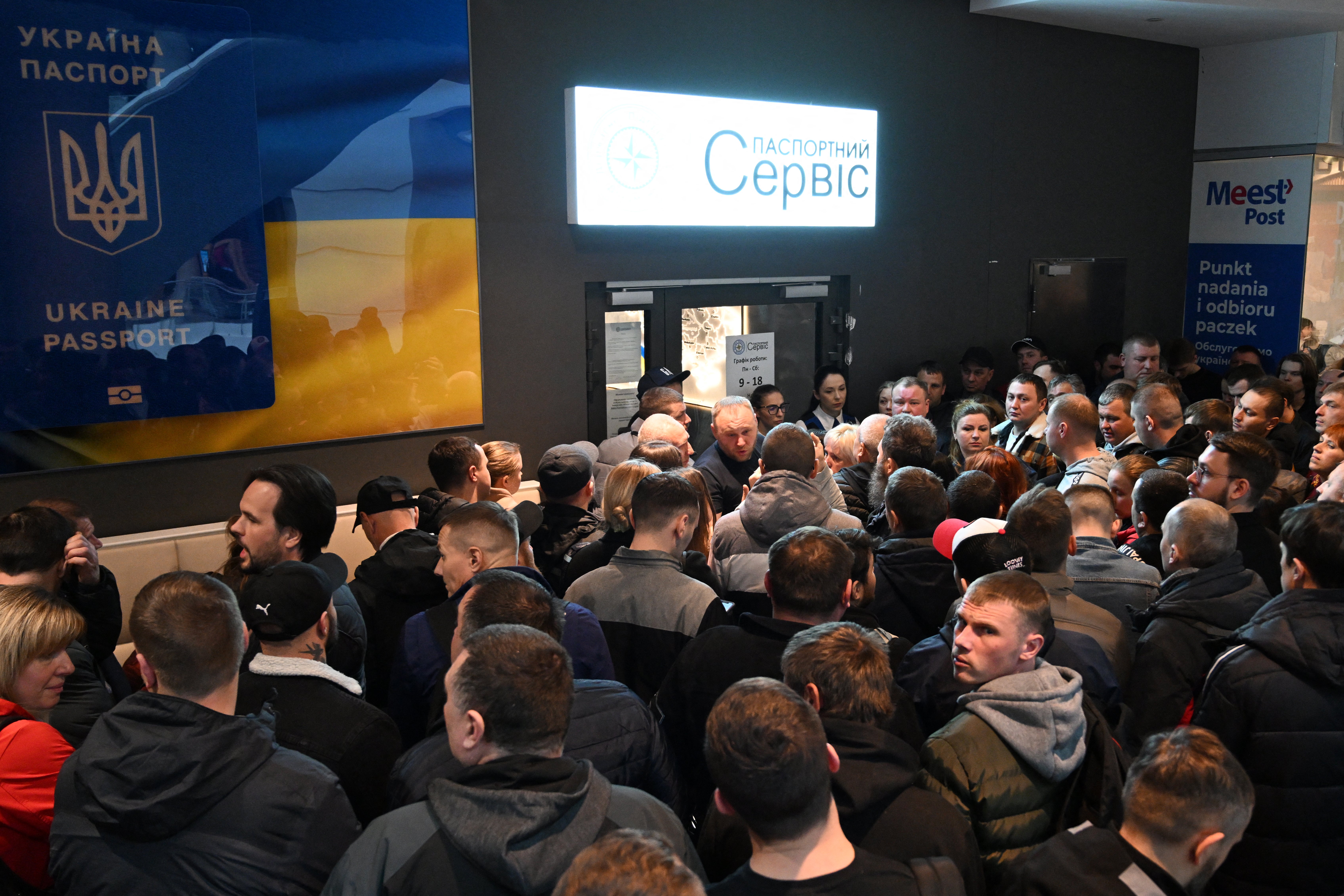 Ukrainians gather in front of a closed Ukraine’s passport service point at the shopping center in Warsaw, Poland