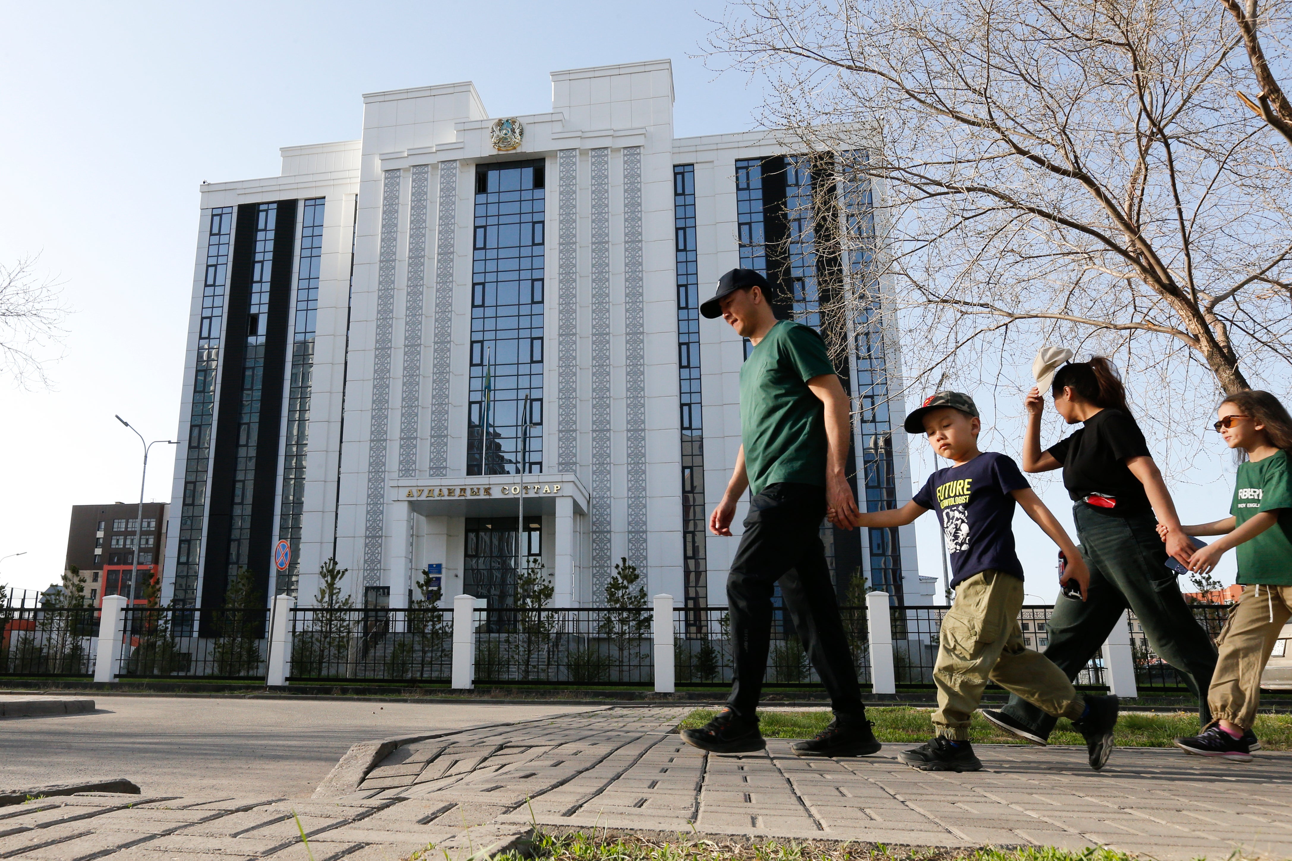 A family walks past the courthouse where the trial of former Economics Minister Kuandyk Bishimbayev is taking place