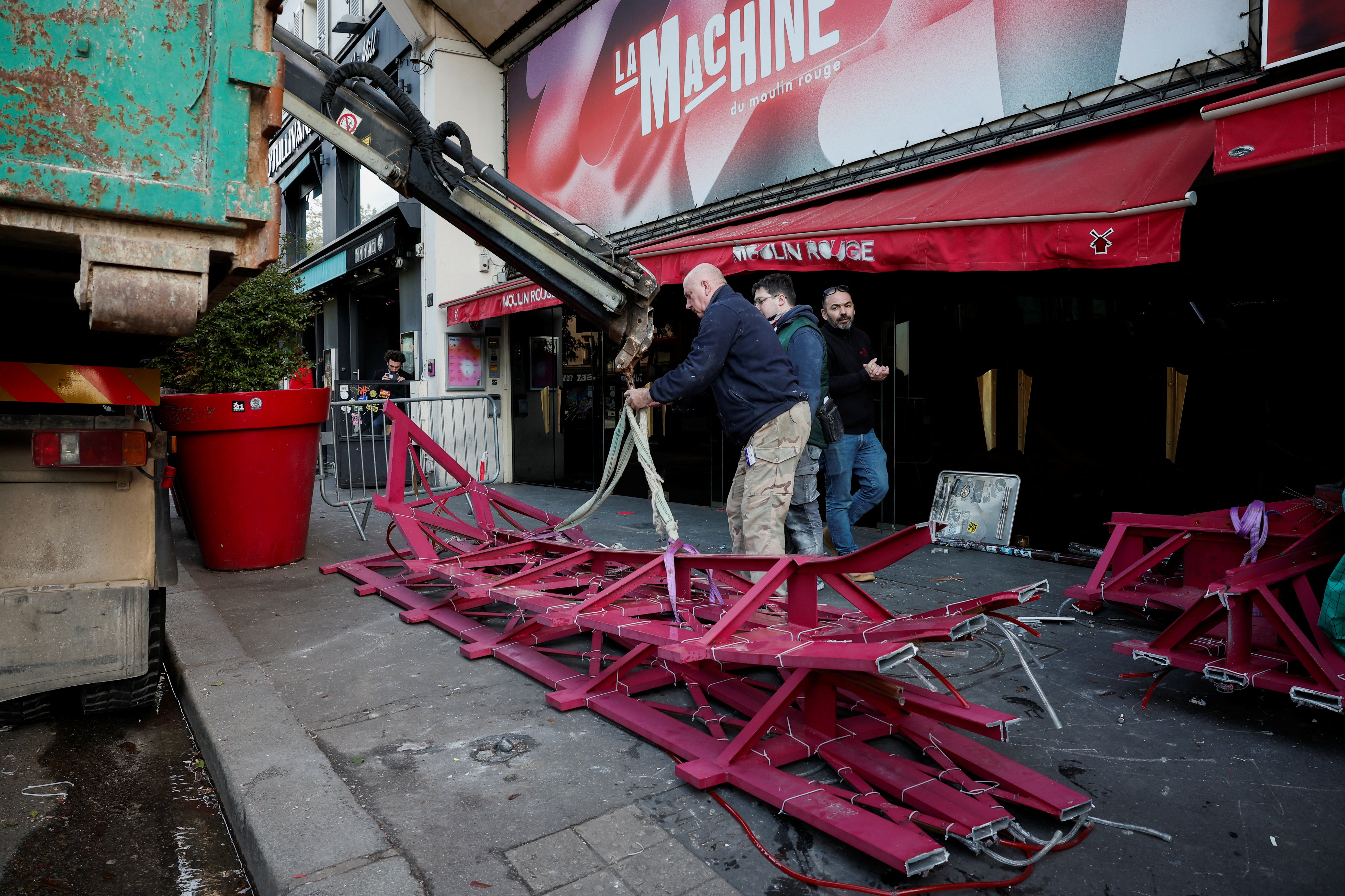 The broken sails of the landmark red windmill atop the Moulin Rouge, Paris' most famous cabaret club, are taken away