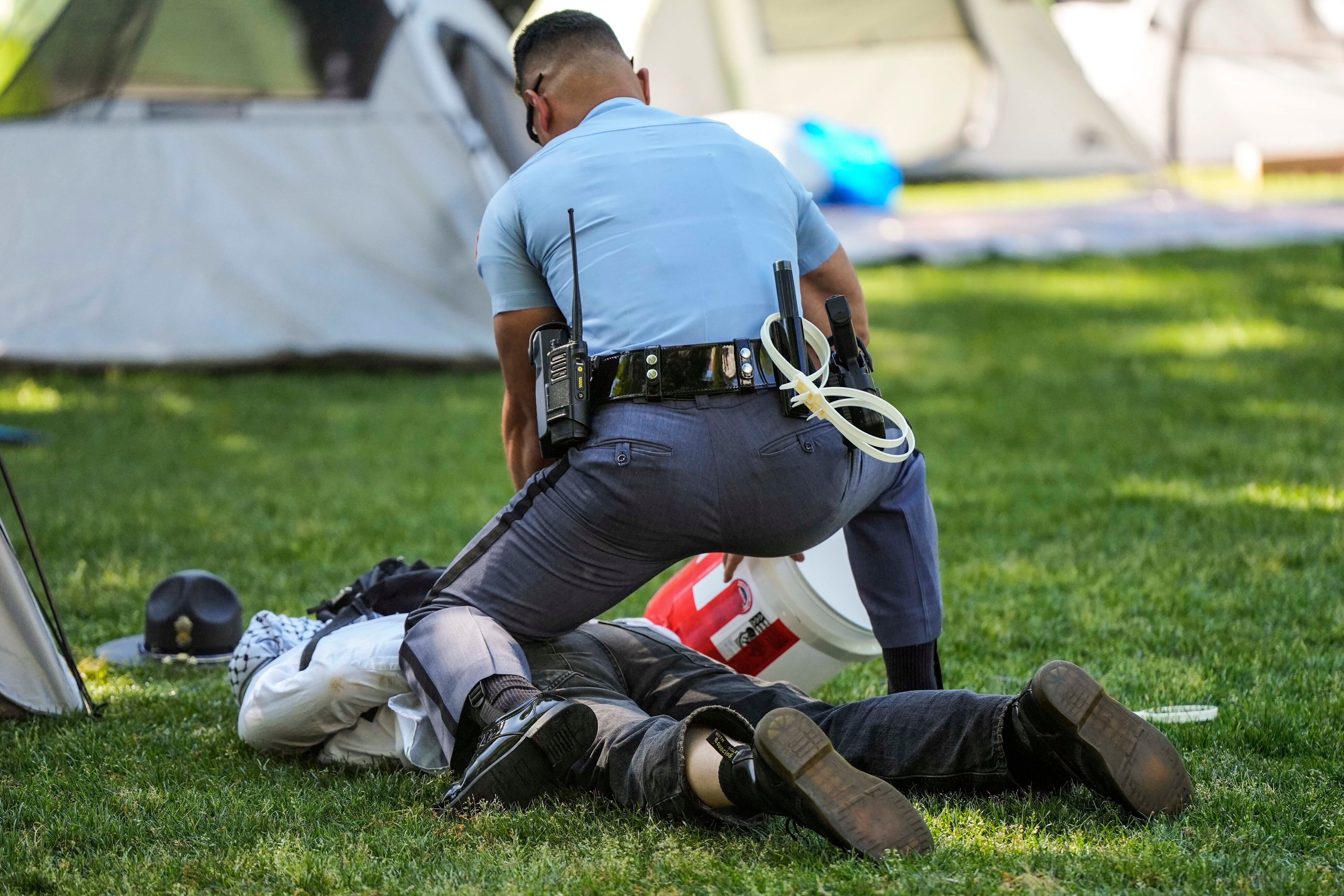 A Georgia State Patrol officer detains a protester on the campus of Emory University