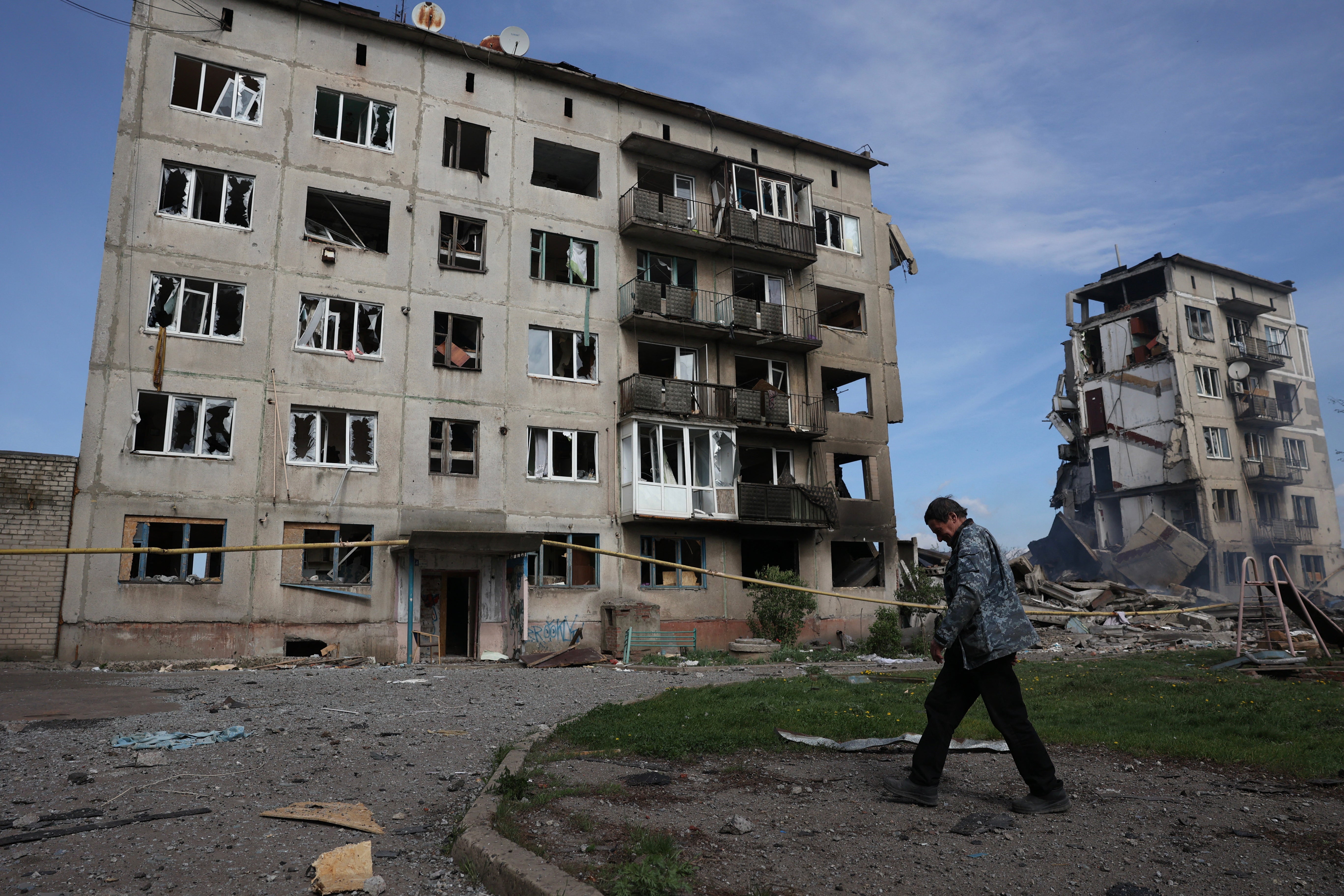 A local resident walks past apartment buildings destroyed by air bomb in the village of Ocheretyne not far from Avdiivka town in the Donetsk region