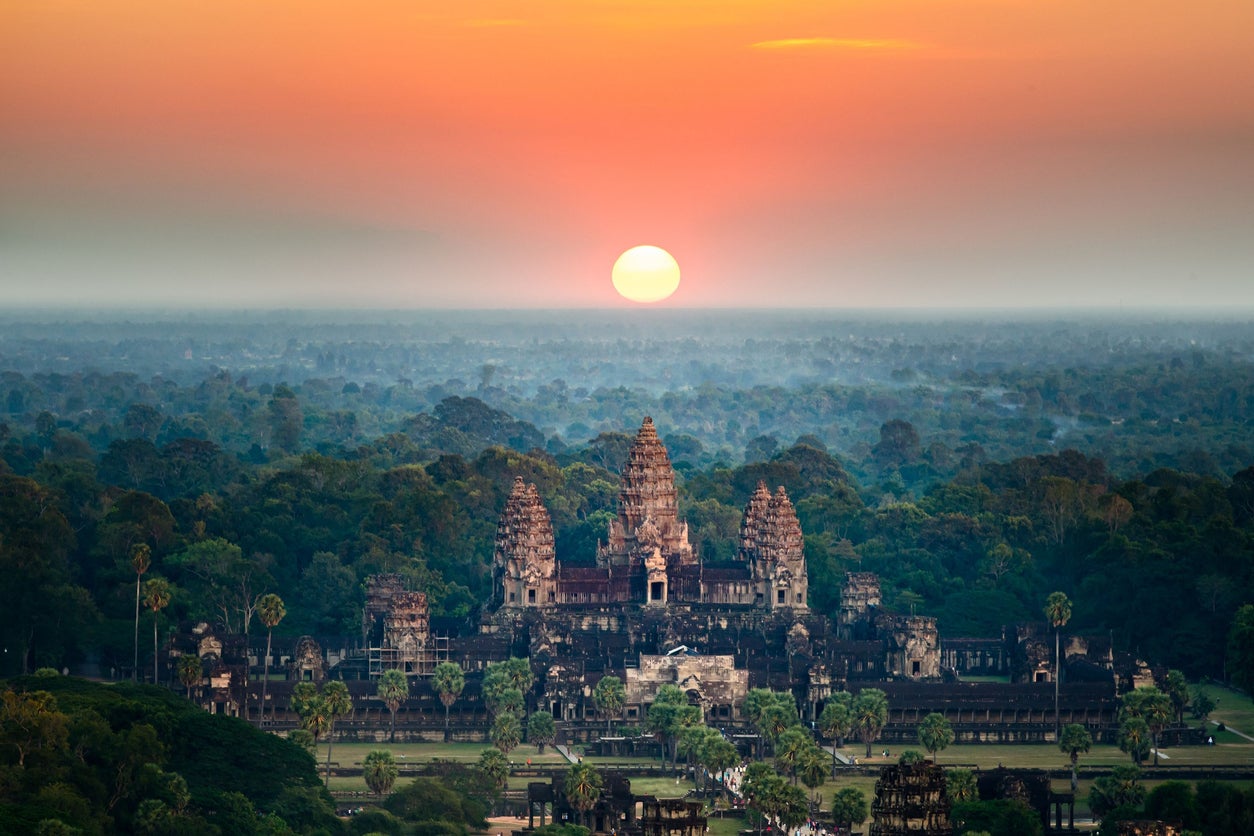 A bird’s eye view of the Angkor Wat temple surrounded by greenery at sunset in Cambodia