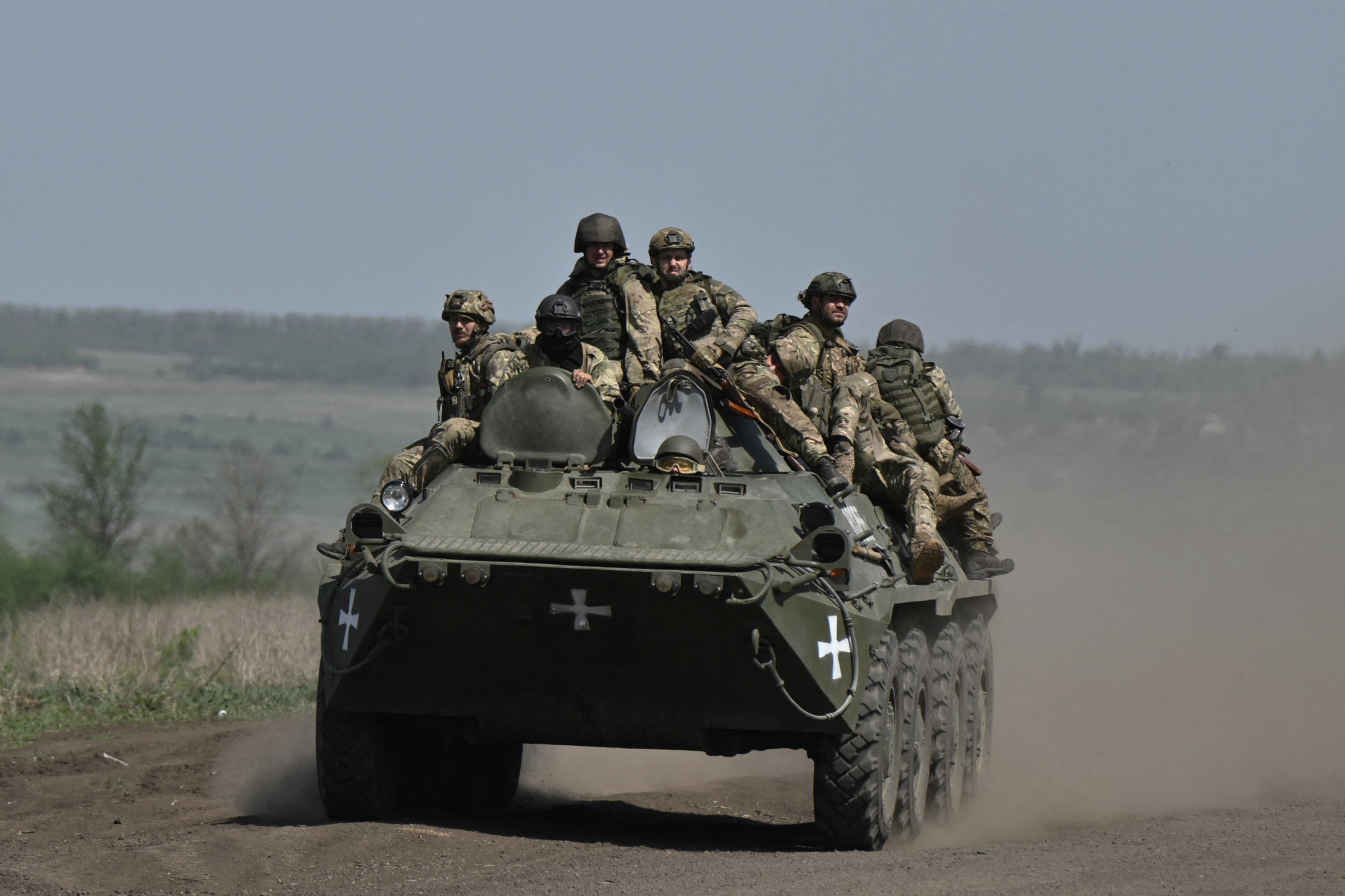 Ukrainian servicemen ride on an armoured personnel carrier in a field near Chasiv Yar