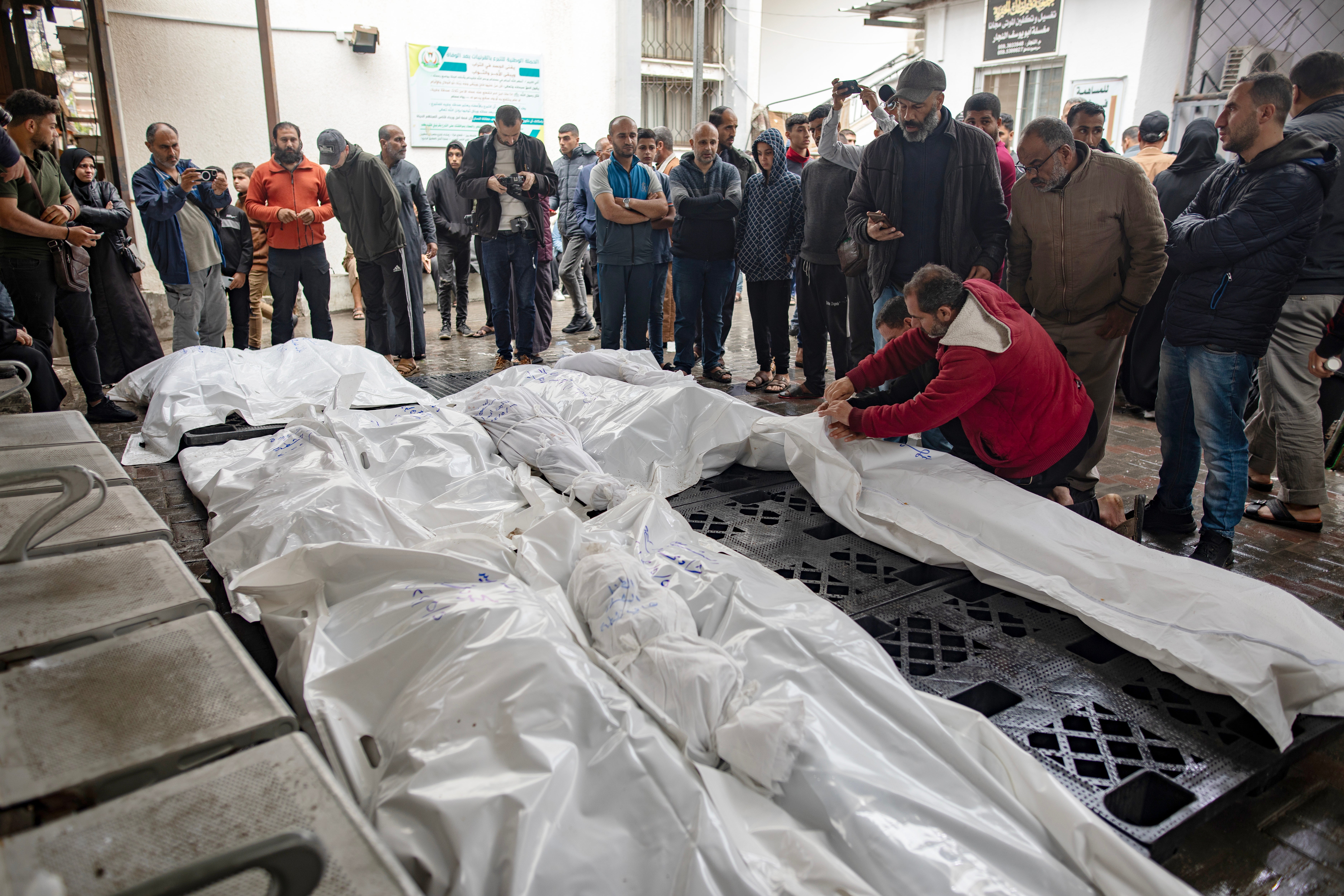 Relatives of Palestinians killed during an Israeli air strike mourn next to their wrapped bodies outside Al-Najjar Hospital