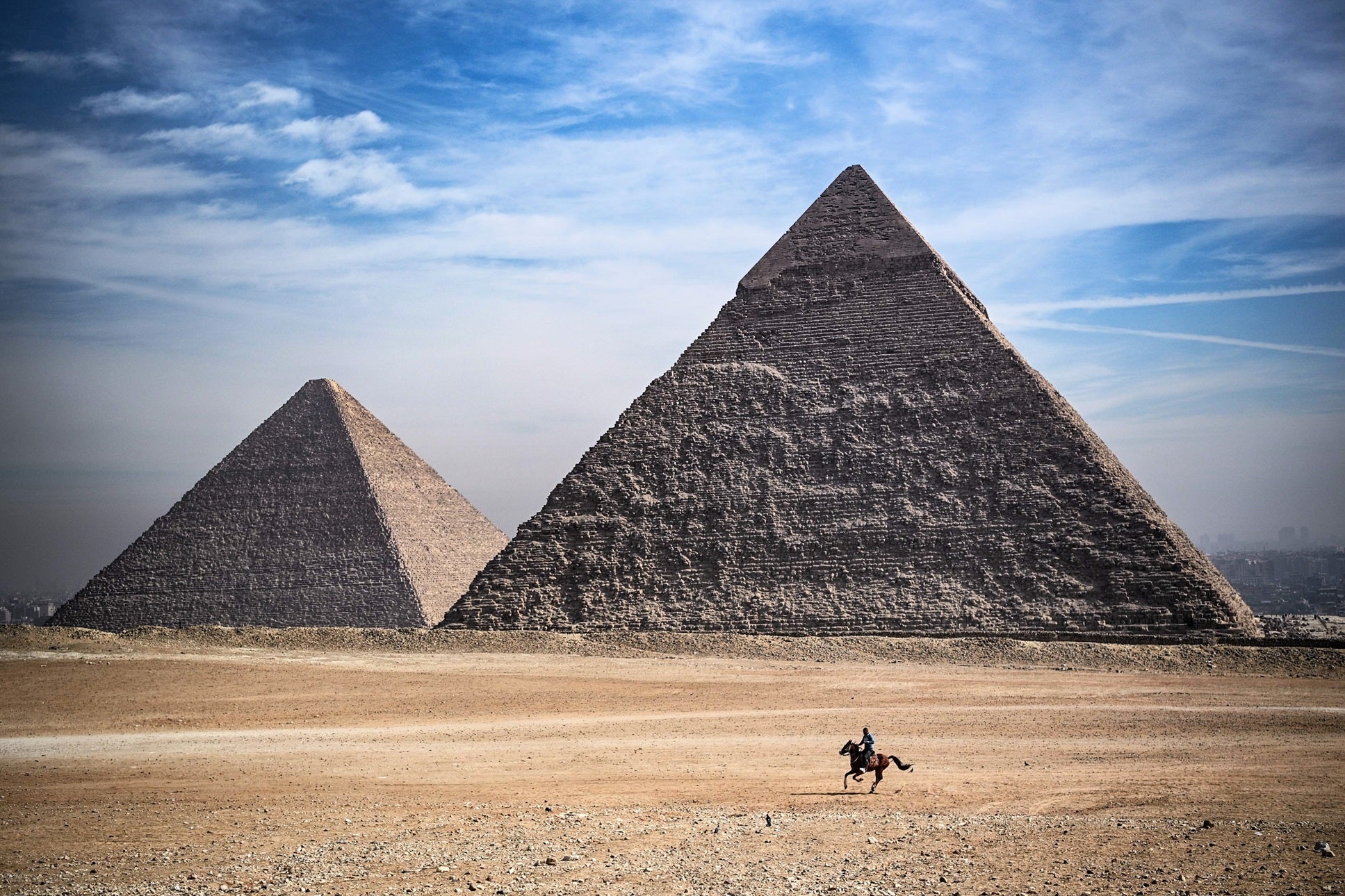 A man rides a horse in front of the Giza pyramids on the outskirts of Cairo, Egypt