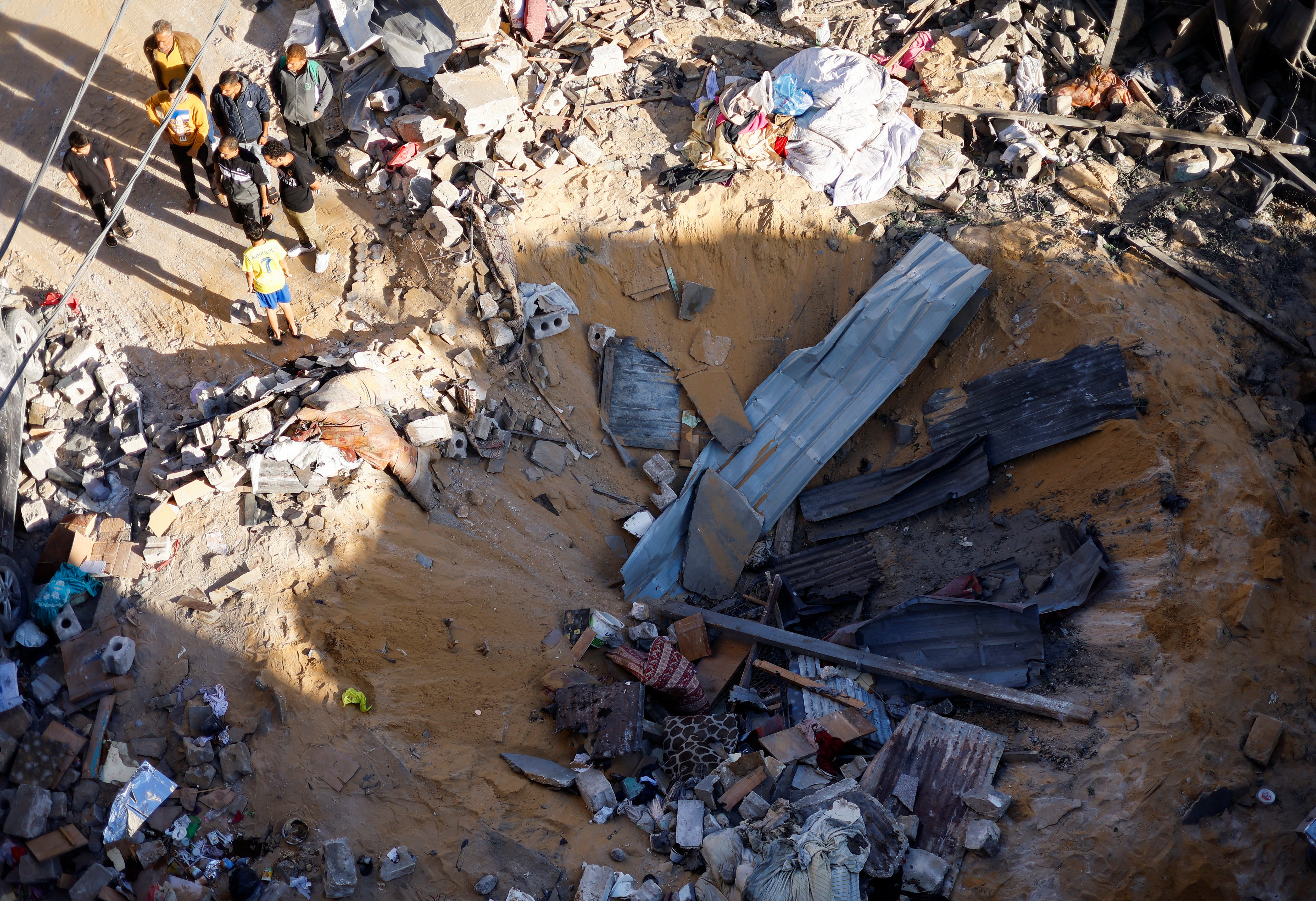 Palestinians inspect the site of an Israeli strike on a house in Rafah, in the southern Gaza Strip