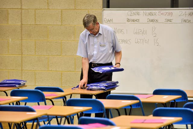 <p>An exam invigilator prepares a maths exam inside a sports hall</p>