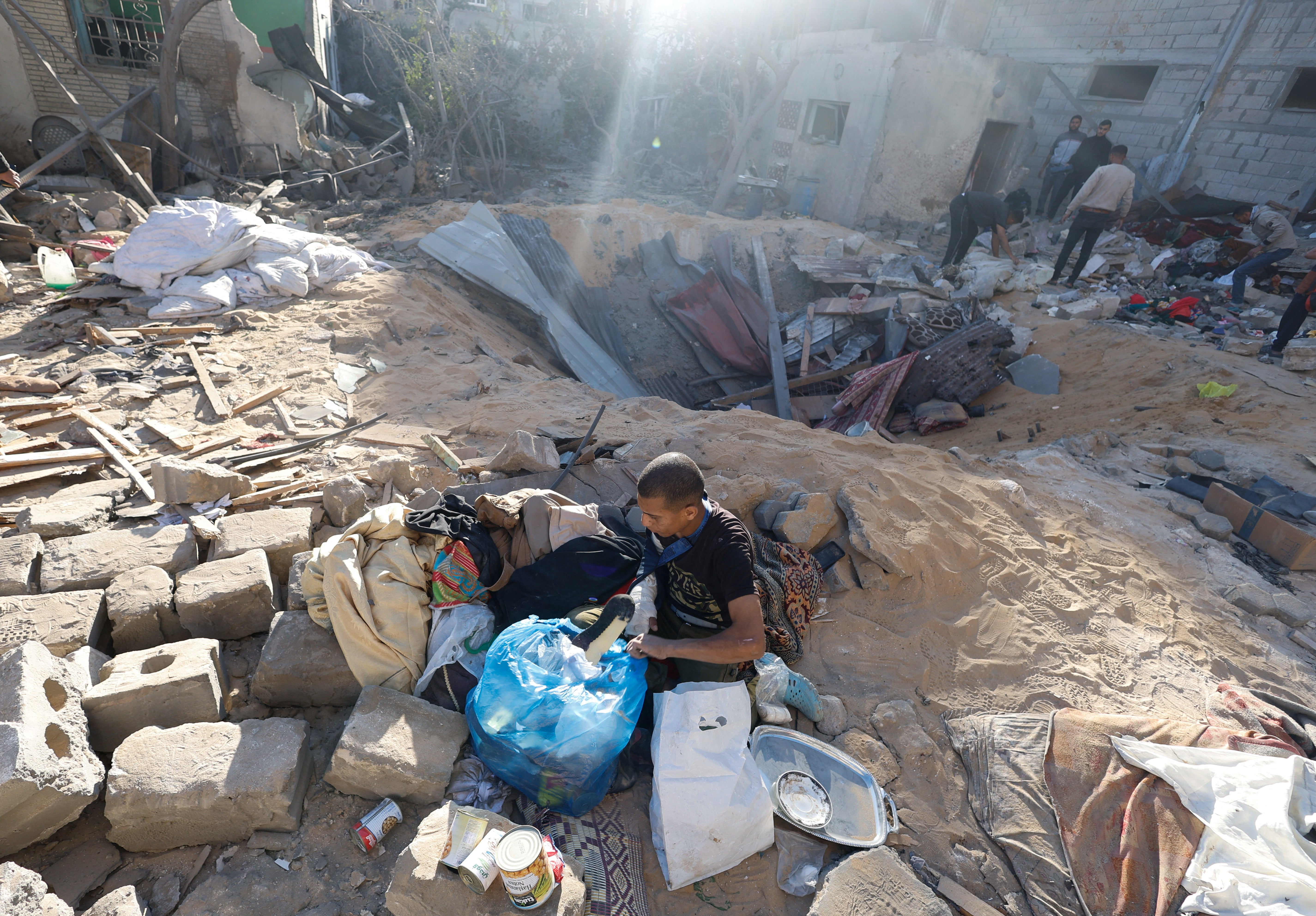 A Palestinian man gathers his belongings after an Israeli airstrike on a house in Rafah