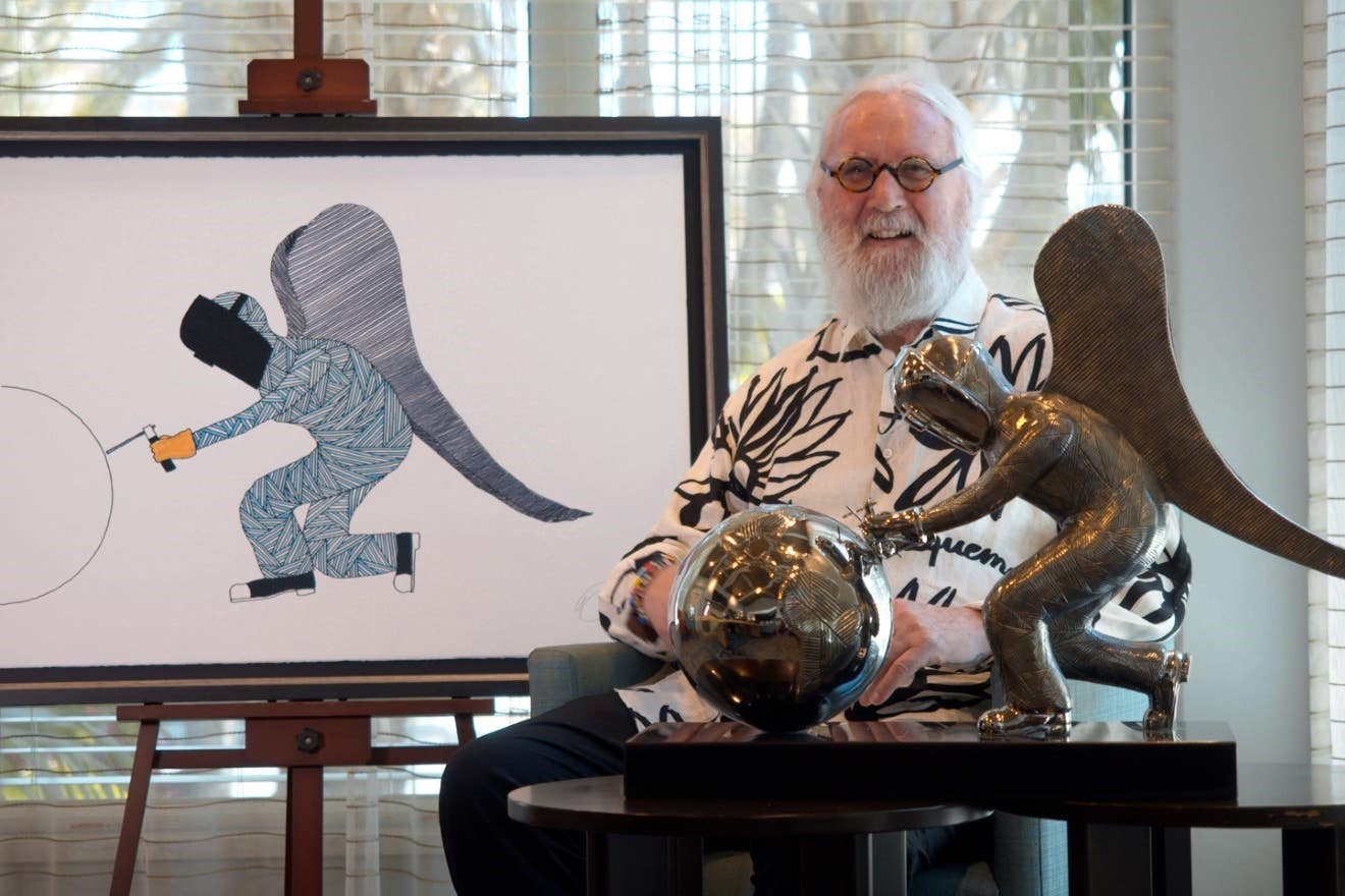 Billy Connolly sits next to his newest painting and sculpture, And On Monday, God Made the World (Castle Fine Art/PA)