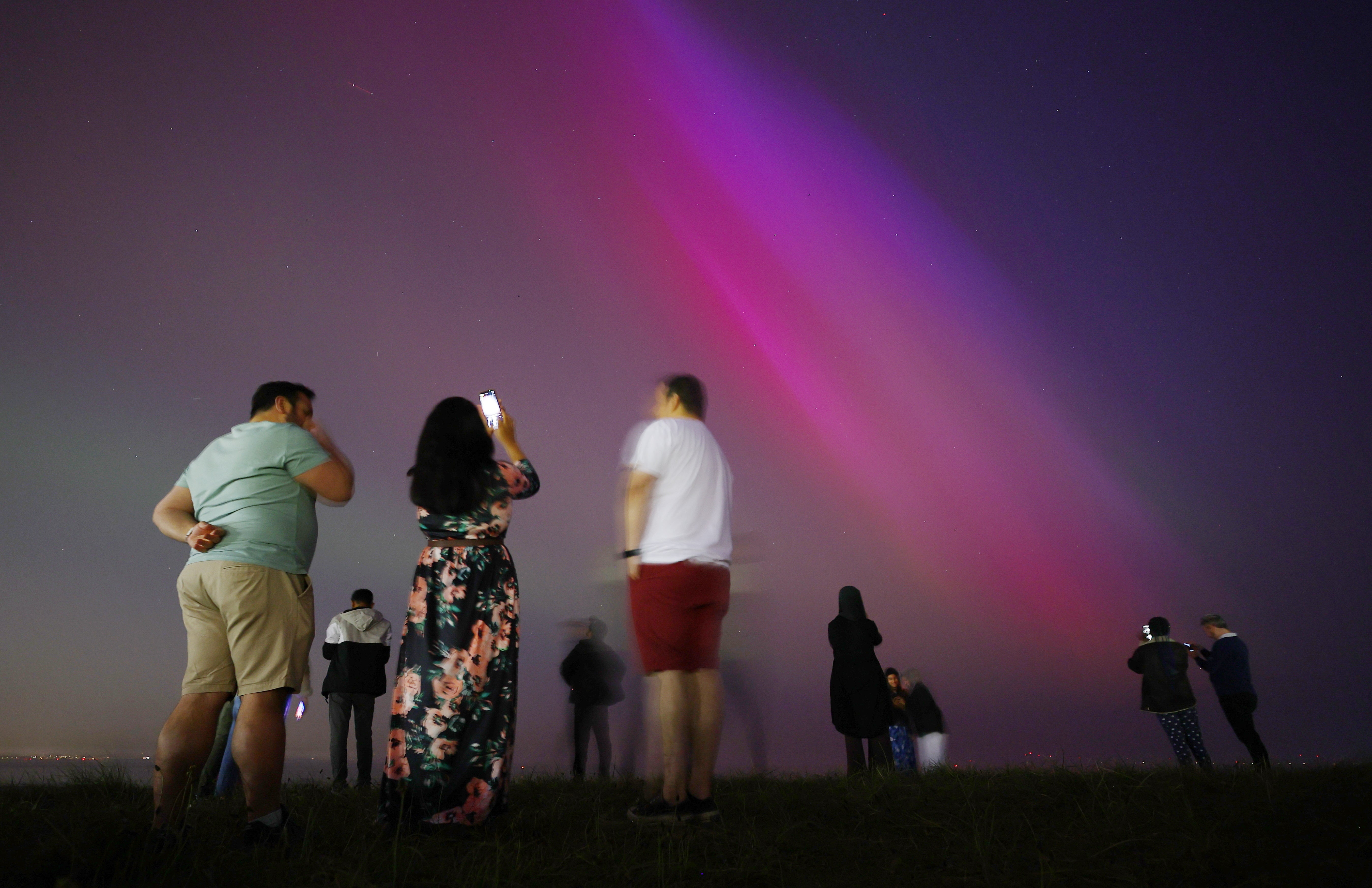 People gather at Crosby Beach to look at the Aurora Borealis, also known as the Northern Lights, in Crosby