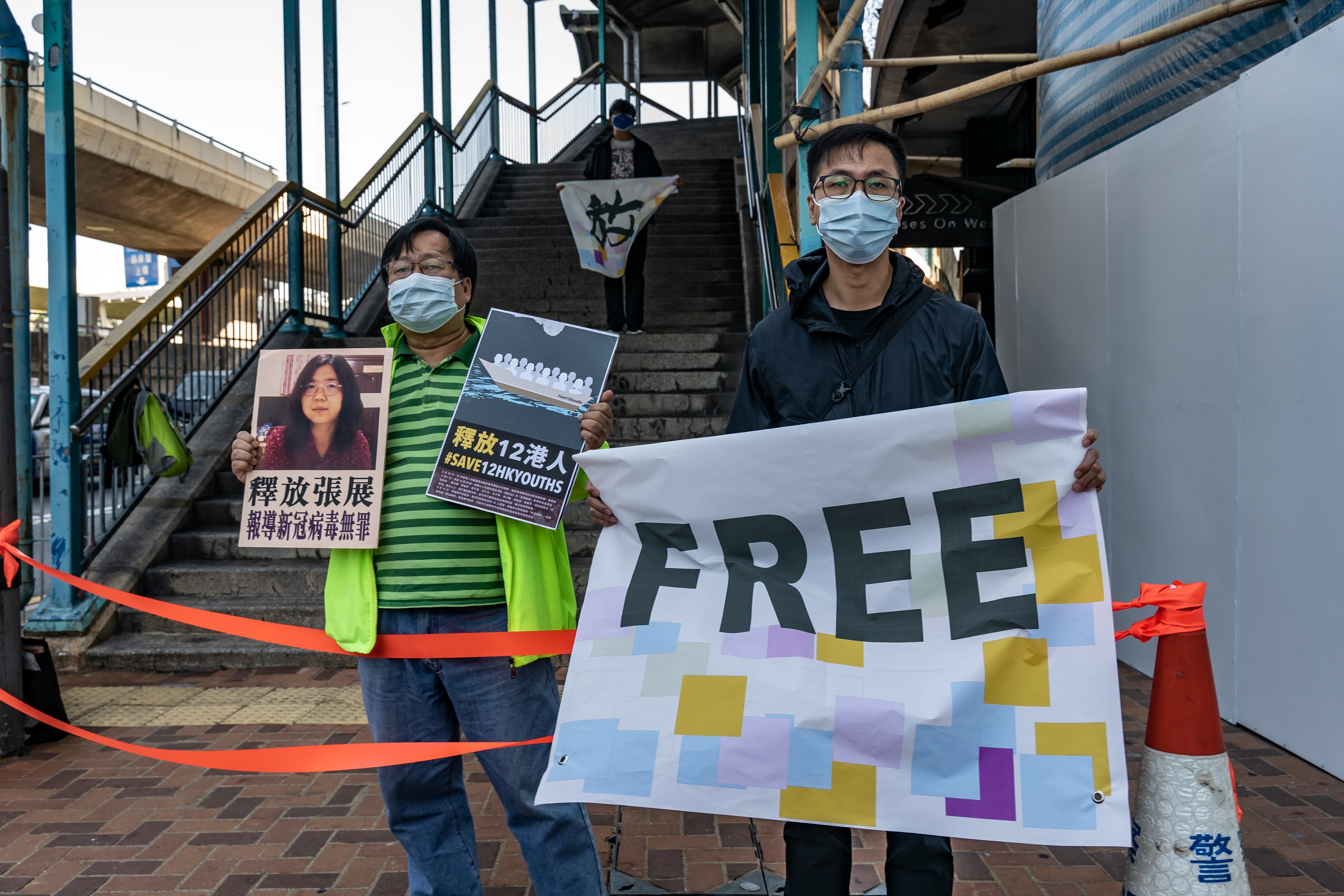 Pro-democracy activists hold placards as they show support for12 Hong Kong residents detained in mainland China and former lawyer Zhang Zhan outside the Liaison Office of the Central People’s Government on December 28, 2020, in Hong Kong