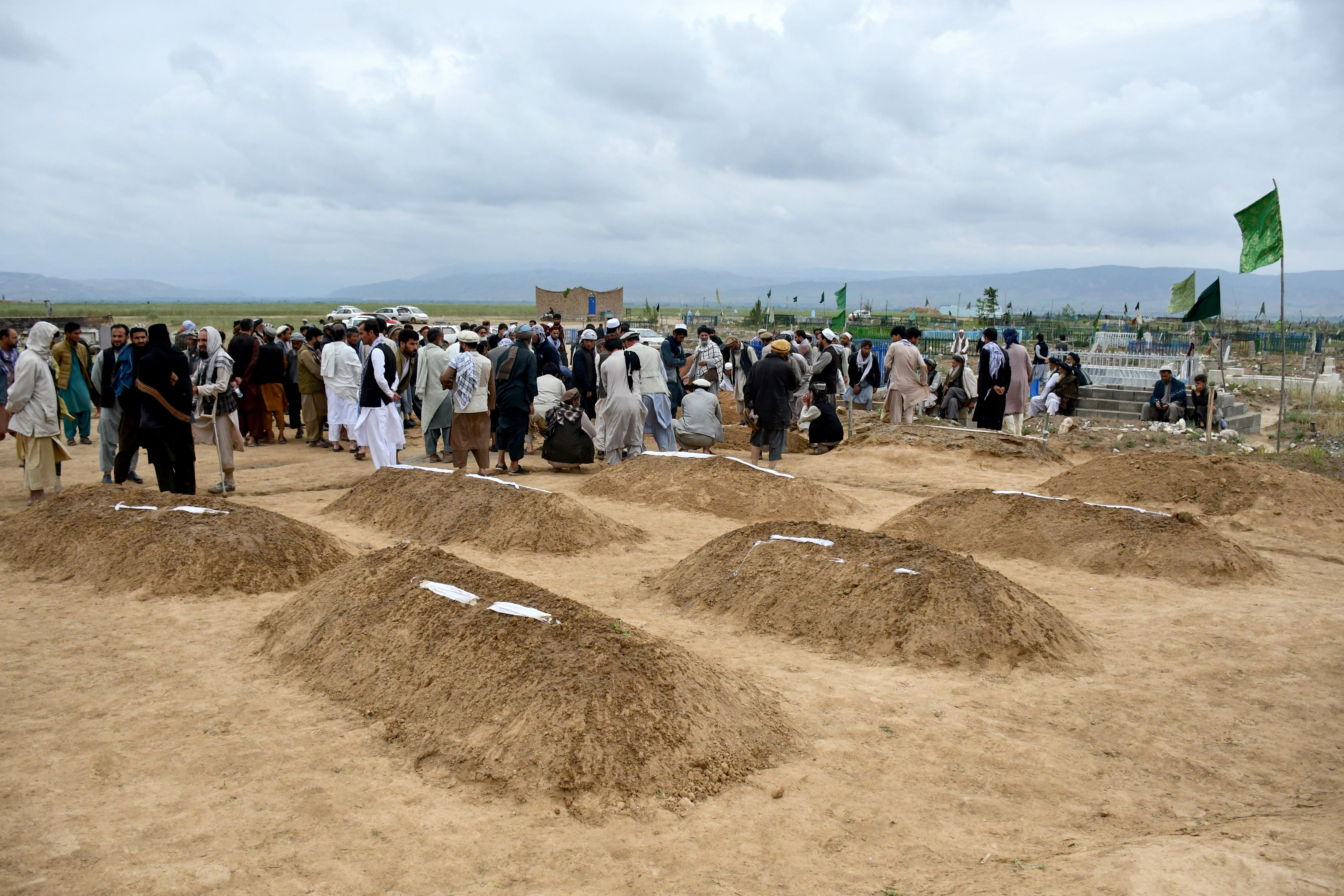 Afghan relatives offer prayers during a burial ceremony, near the graves of victim who lost their lives following flash floods after heavy rainfall at a village in Baghlan-e-Markazi district of Baghlan province on 11 May 2024