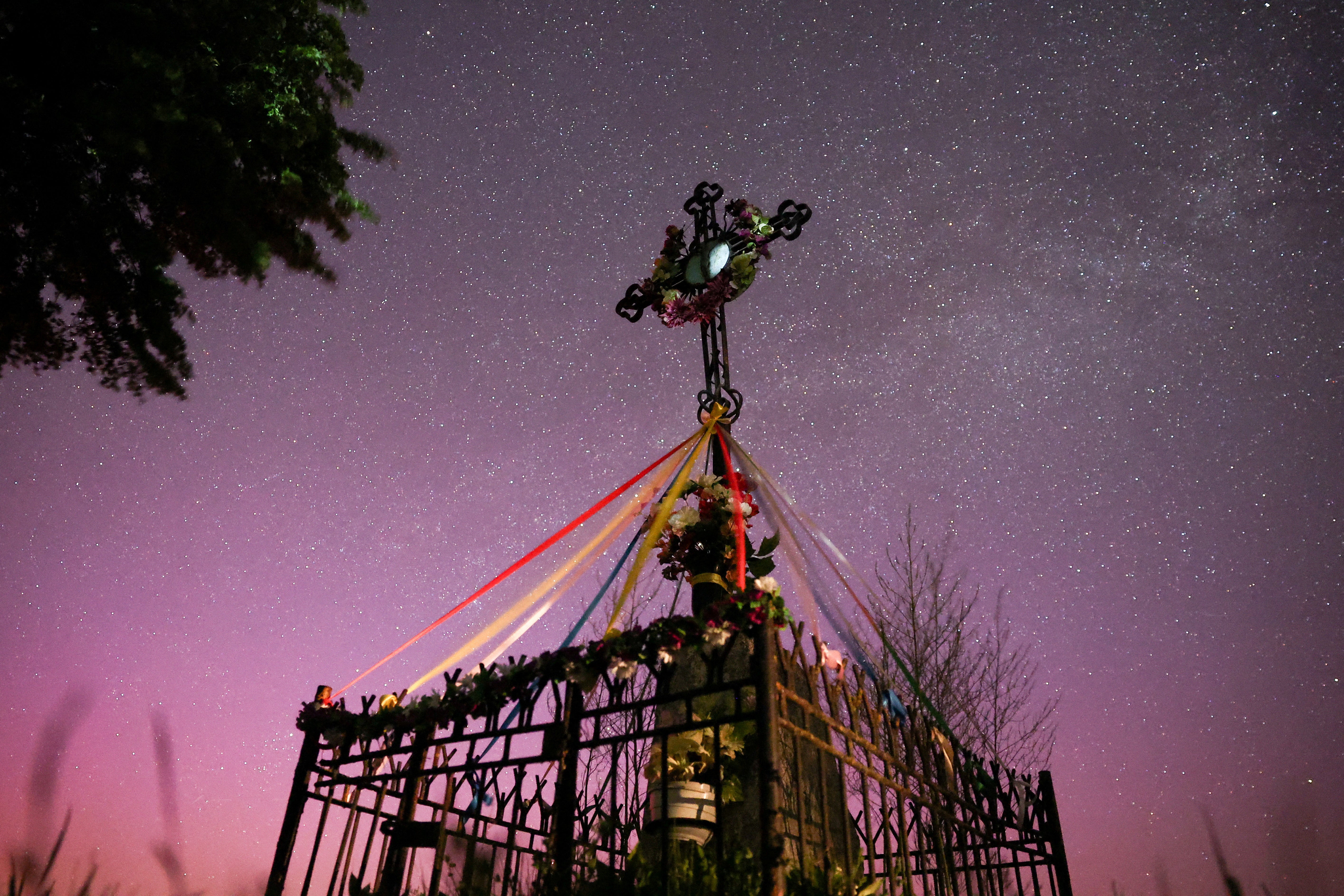 Northern lights are seen over a roadside cross near Mchowo, Poland May 12, 2024