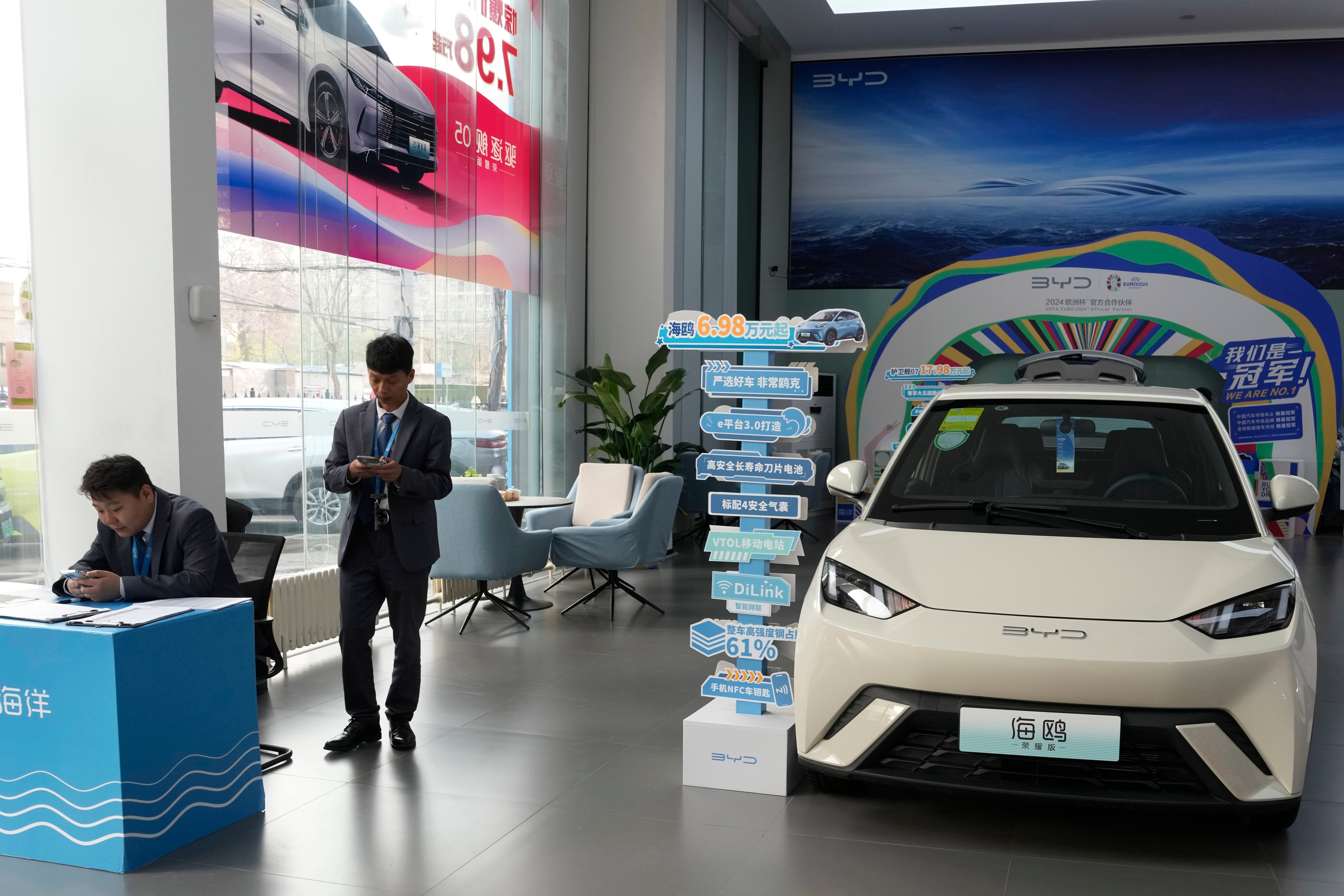 Sales staff stand near the Seagull electric vehicle from Chinese automaker BYD at a showroom in Beijing, Wednesday, April 10, 2024