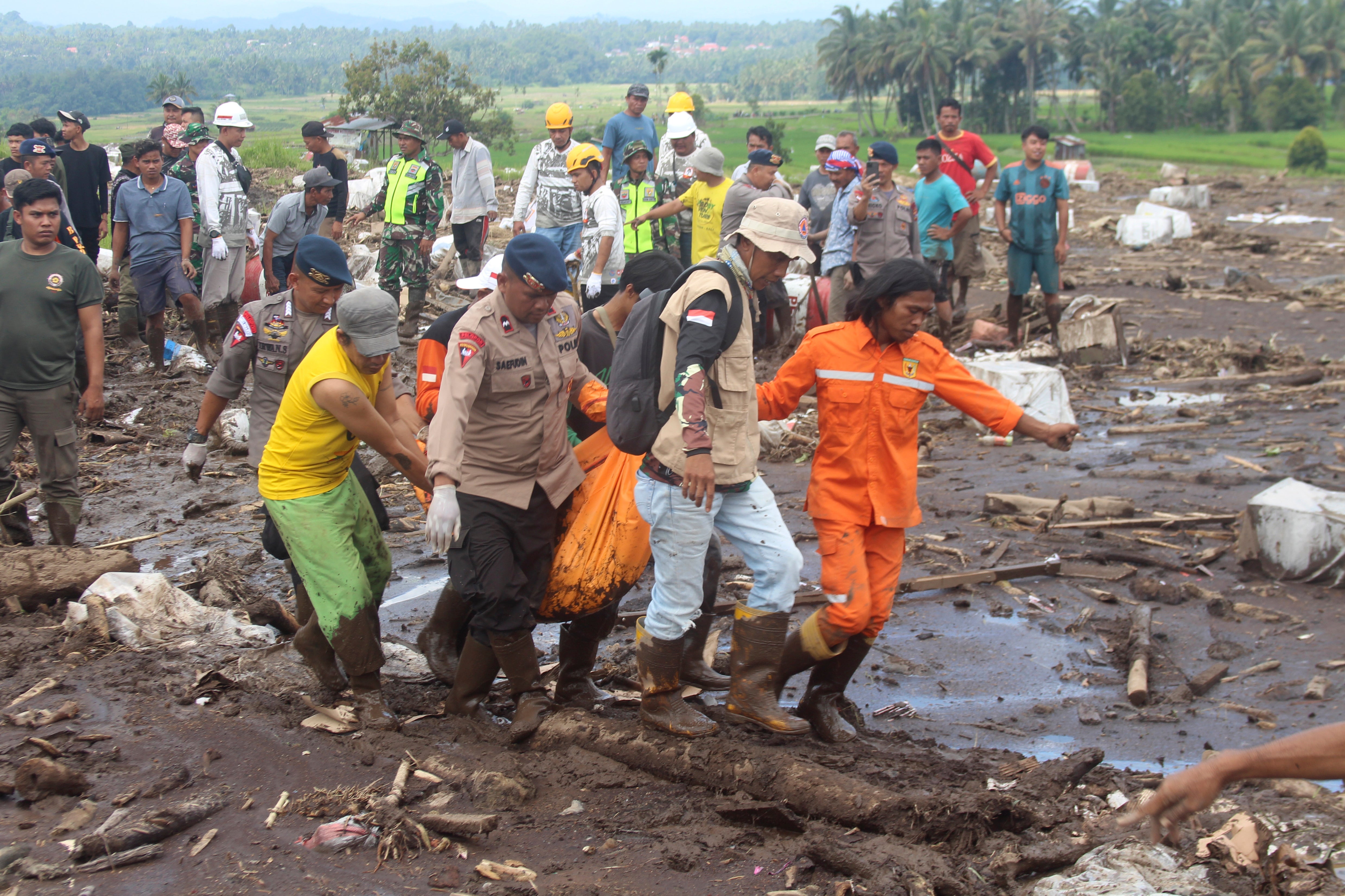 Rescuers carry the body of a victim of a flash flood in Tanah Datar, West Sumatra, Indonesia