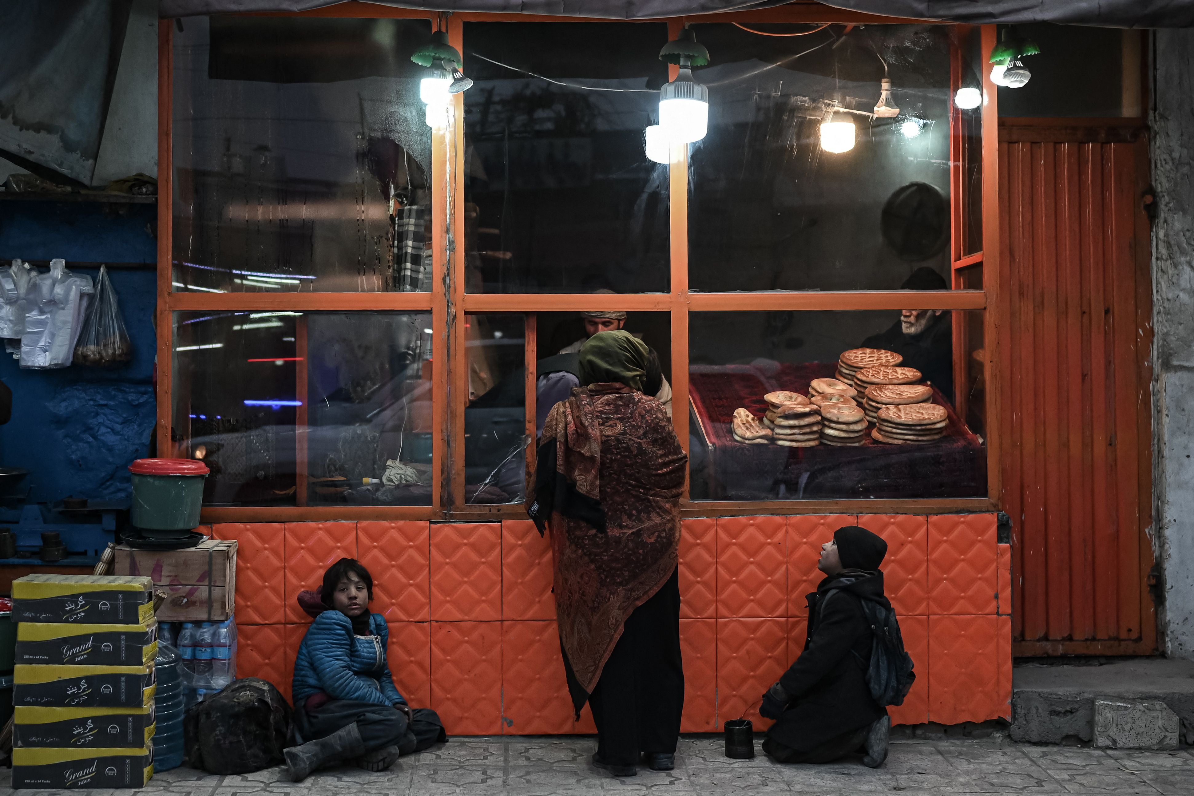 Afghan boys beg for food at a bread shop in Kabul